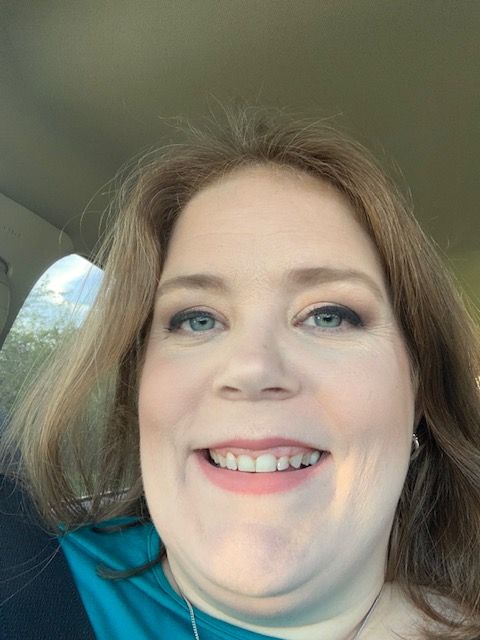 Close-up of smiling woman with light brown hair and blue eyes inside a vehicle.