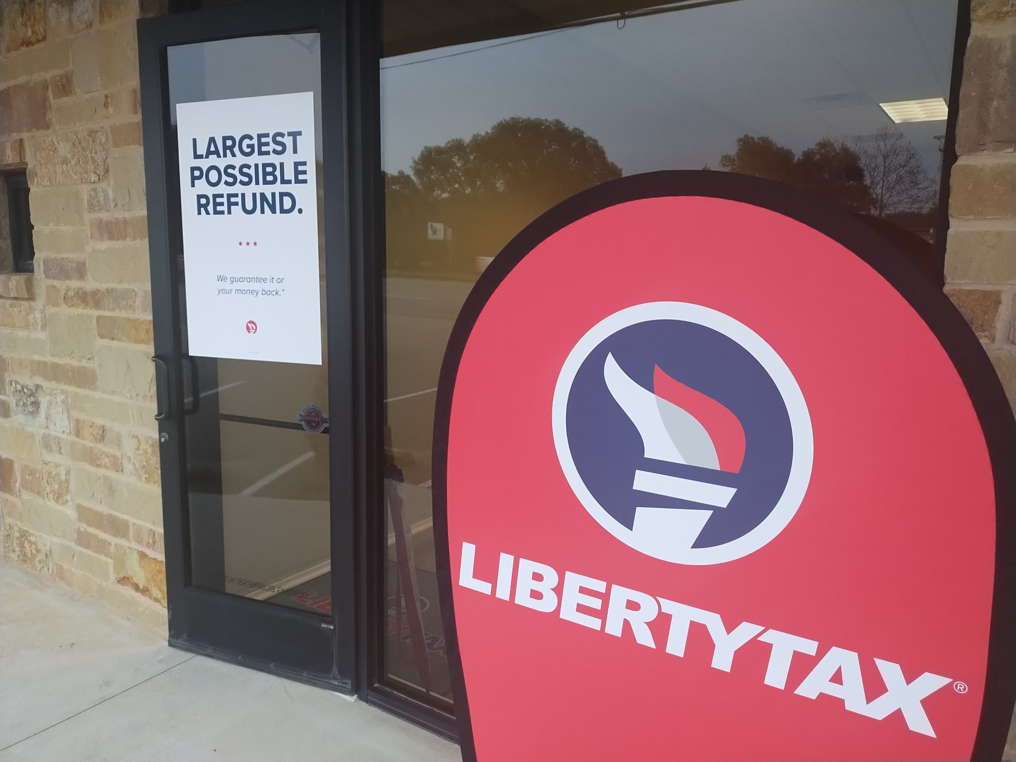 Store entrance with a sign that reads 'Largest possible refund' and a Liberty Tax sign on the window.