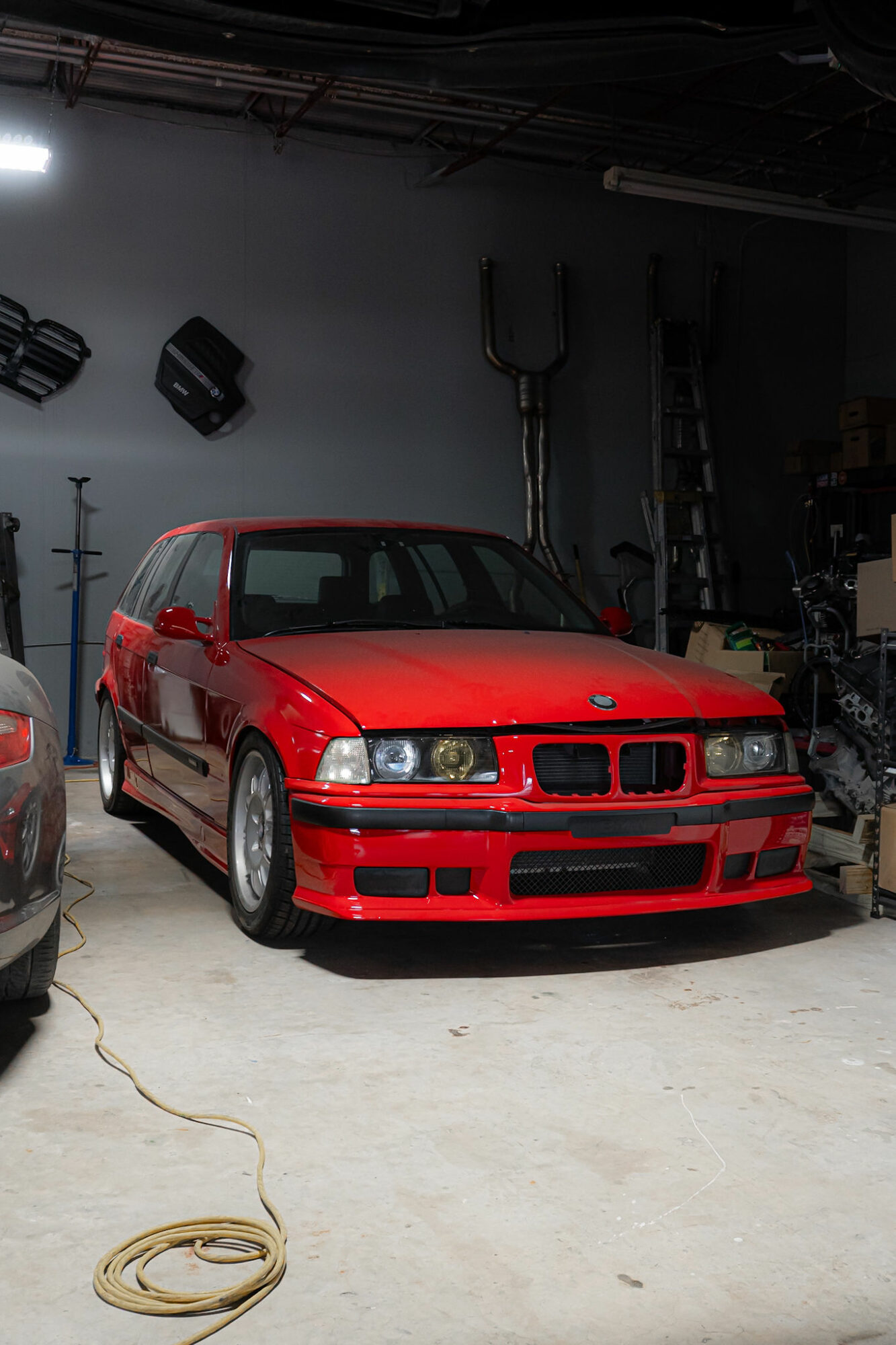 Red car parked indoors with equipment and tools in the background.