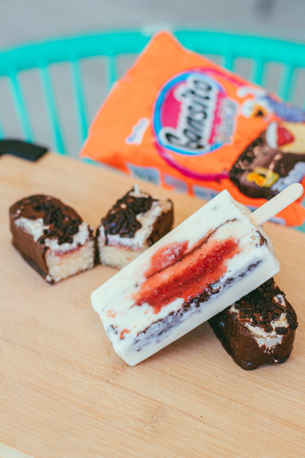 Three ice cream bars on a wooden surface with a bag of Popsicle in the background.