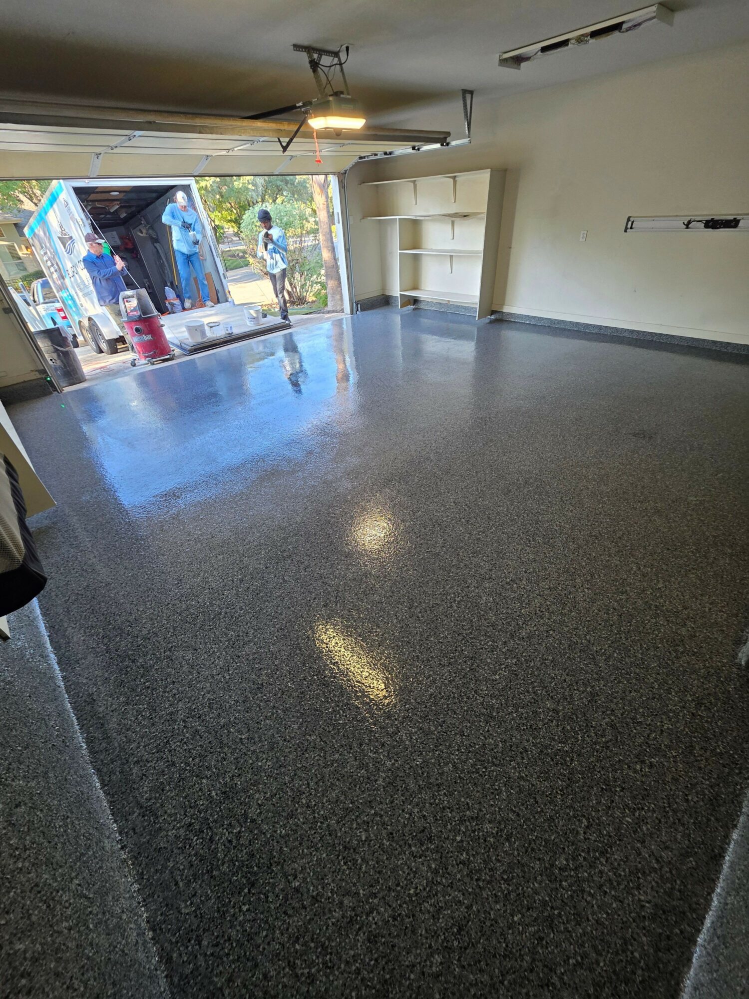 Empty room with a dark countertop, open door, and a view outside through a window, sunlight on the floor.
