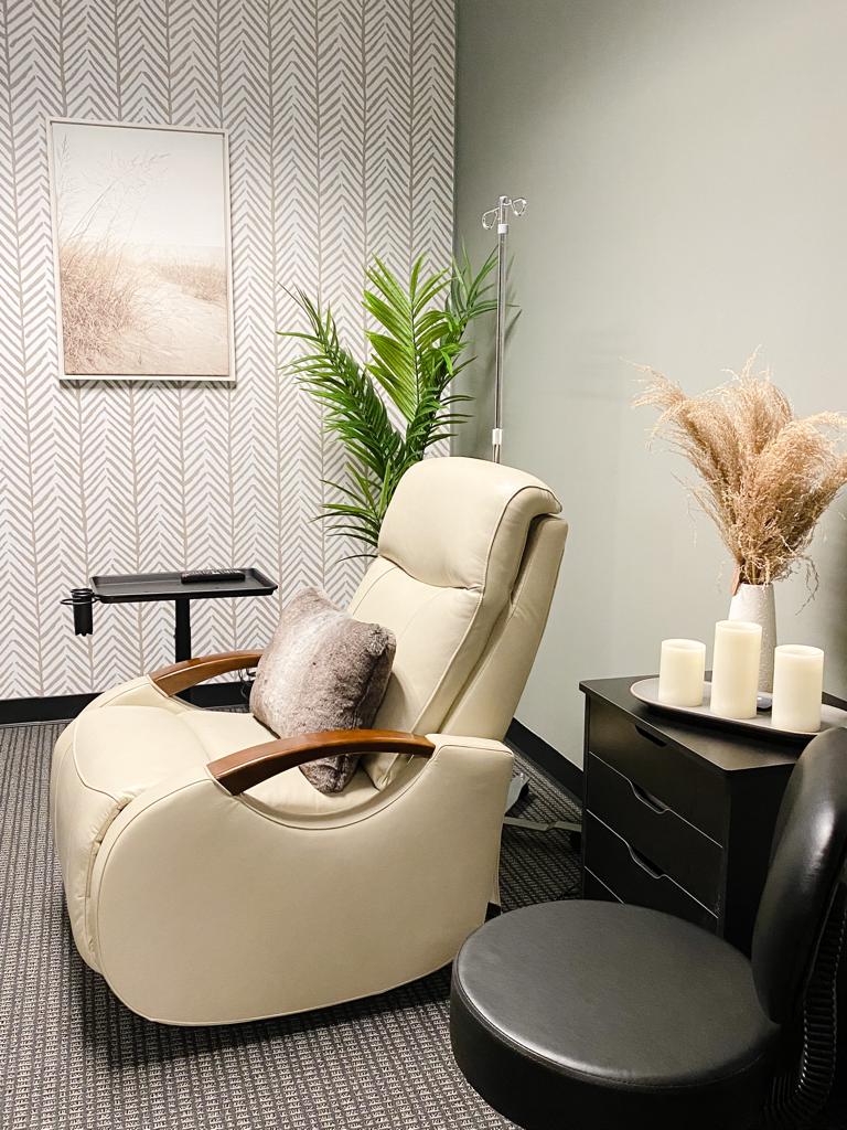 Comfortable cream-colored recliner with a pillow, next to a black side table with candles, in a cozy room.