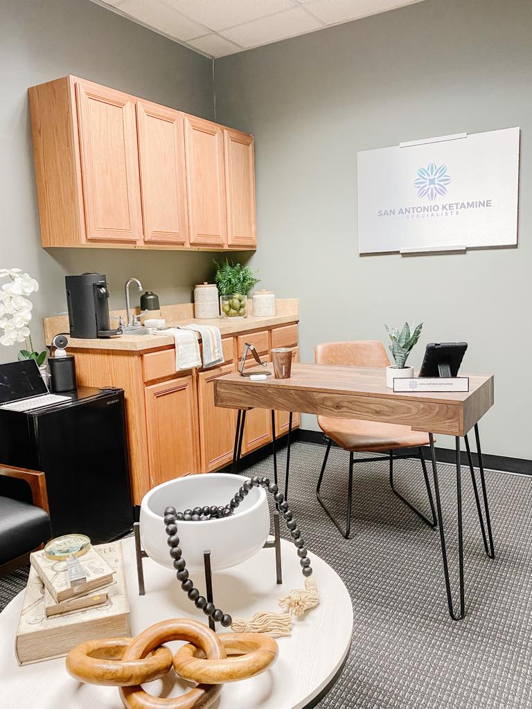 Office with a desk, chairs, cabinet, and wall art, featuring a neutral color scheme and organized workspace.