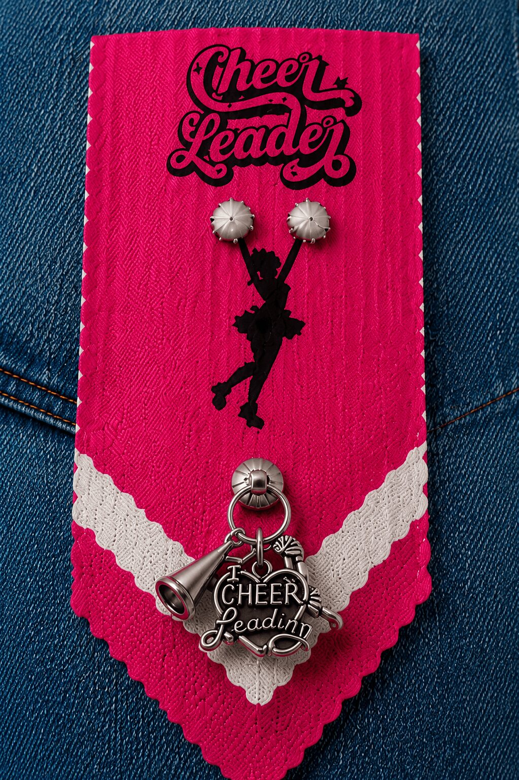 Pink fabric with black text reading 'Cheer Leader' and a silhouette of a girl holding pom-poms, with a silver cheerleading charm attached.