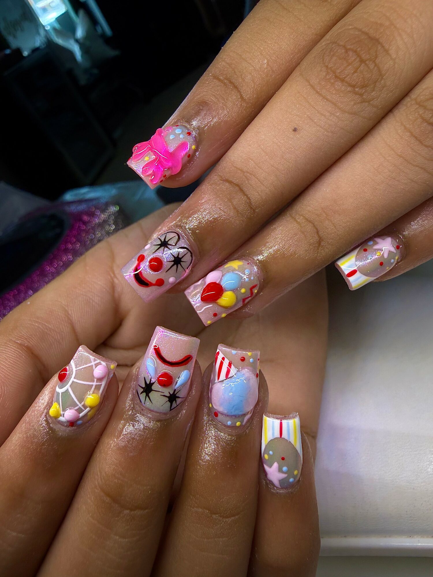 Close-up of hands with colorful holiday-themed nail art, including snowmen, Christmas trees, and ornaments.