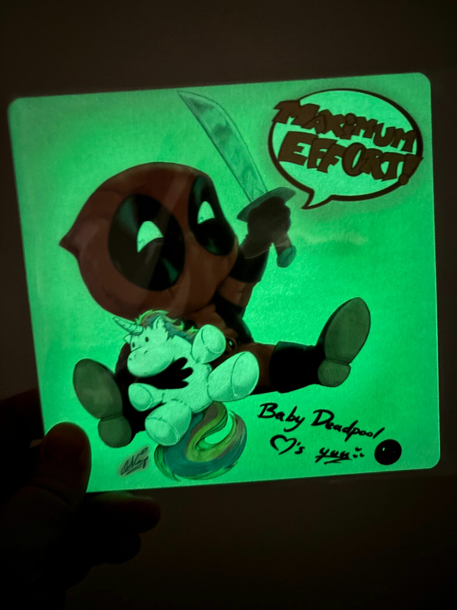 Glow-in-the-dark poster featuring a cartoon character with a speech bubble, signed by Billy D. D. with a date, held in hand.