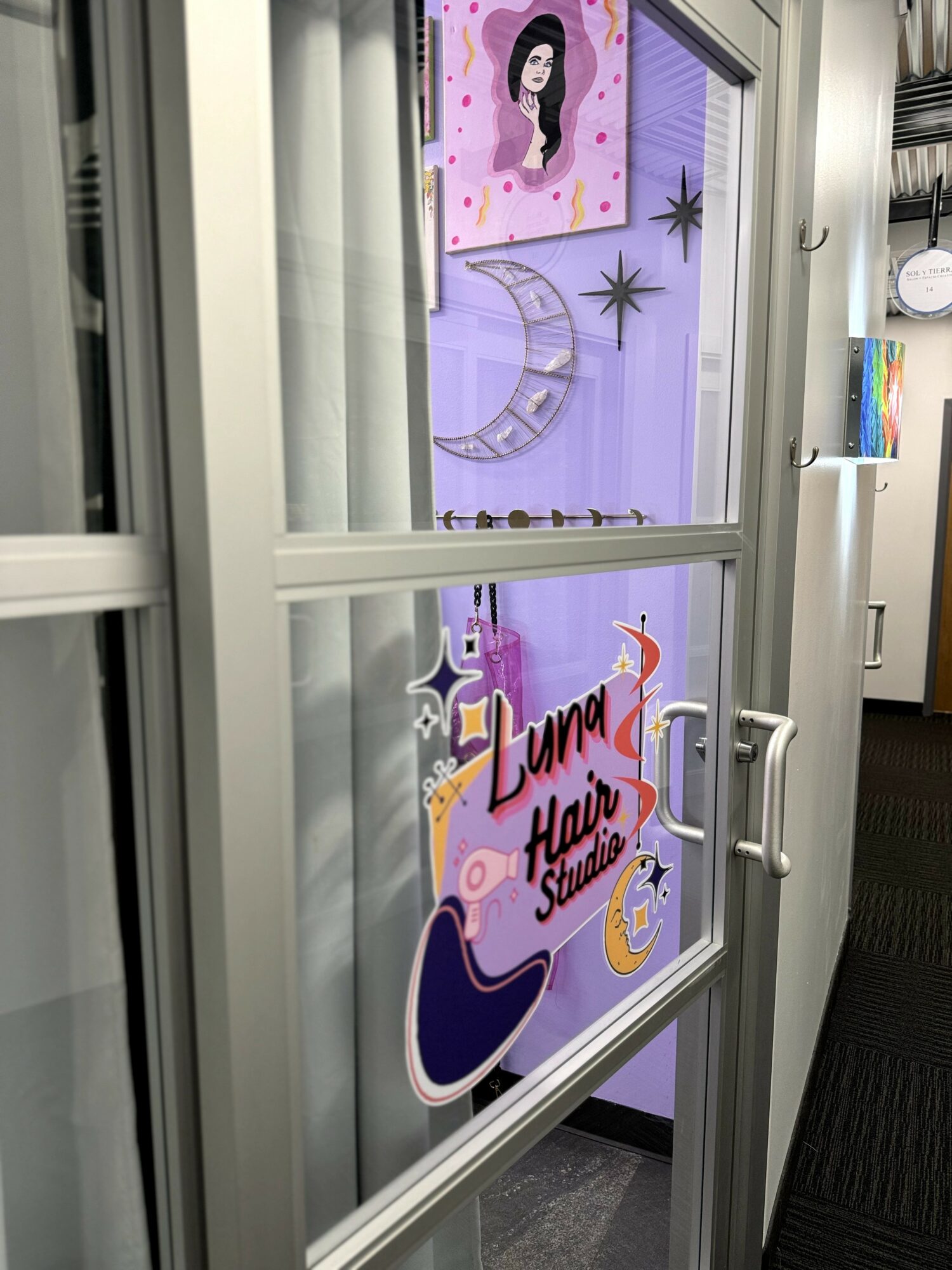 Decorative window with artwork including a girl, moon, stars, and a sign reading 'Lana Hair Studio'.