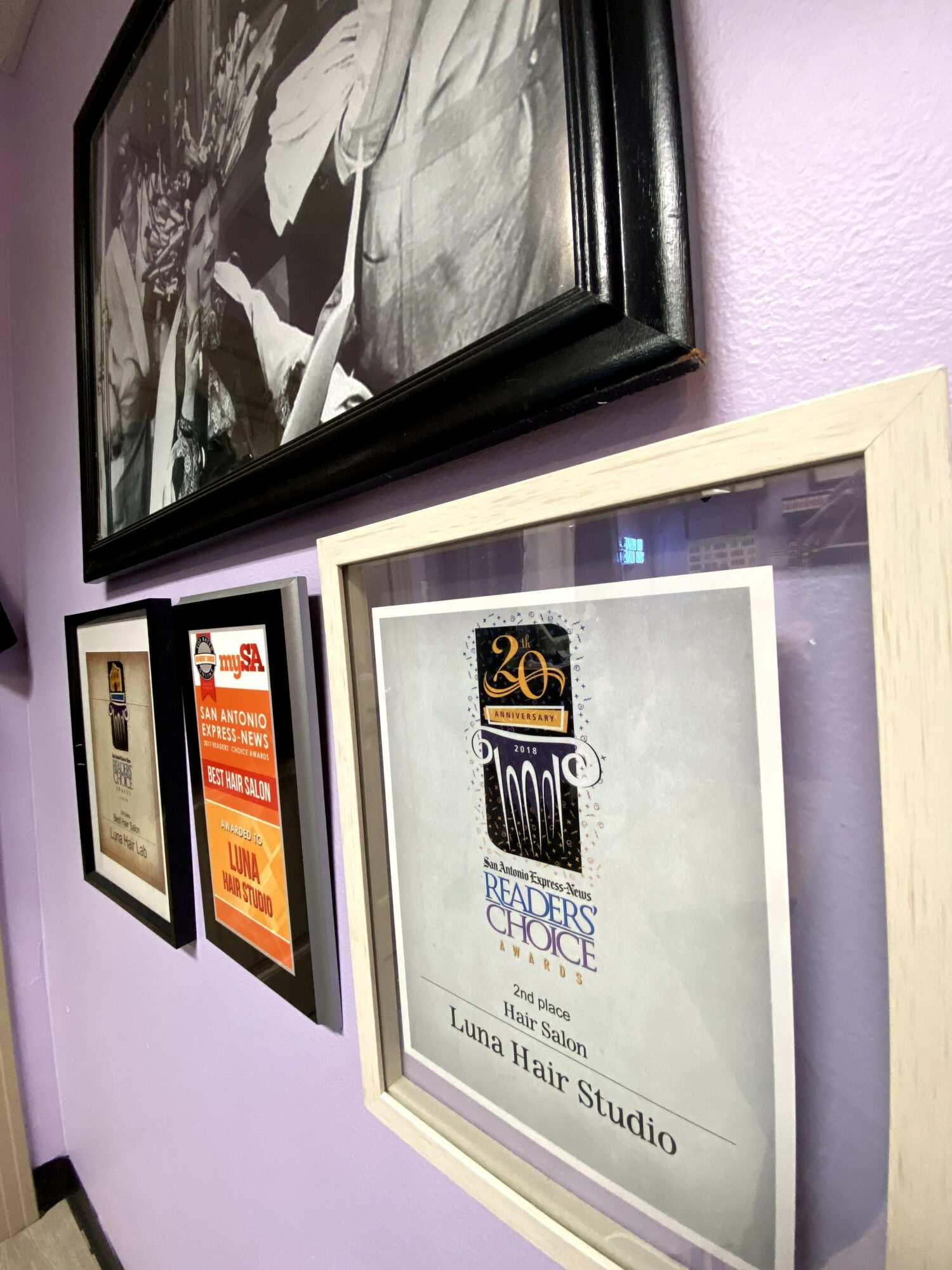 Framed certificate or award on a wall, with other framed items nearby, against a light-colored wall.