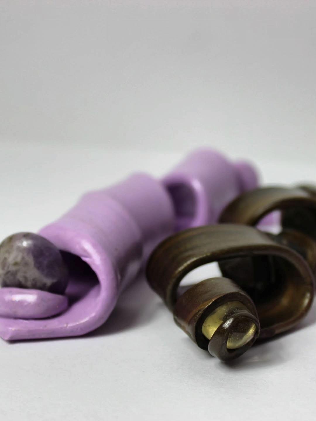 Purple and brown hair curlers with a gray stone, on a white surface.