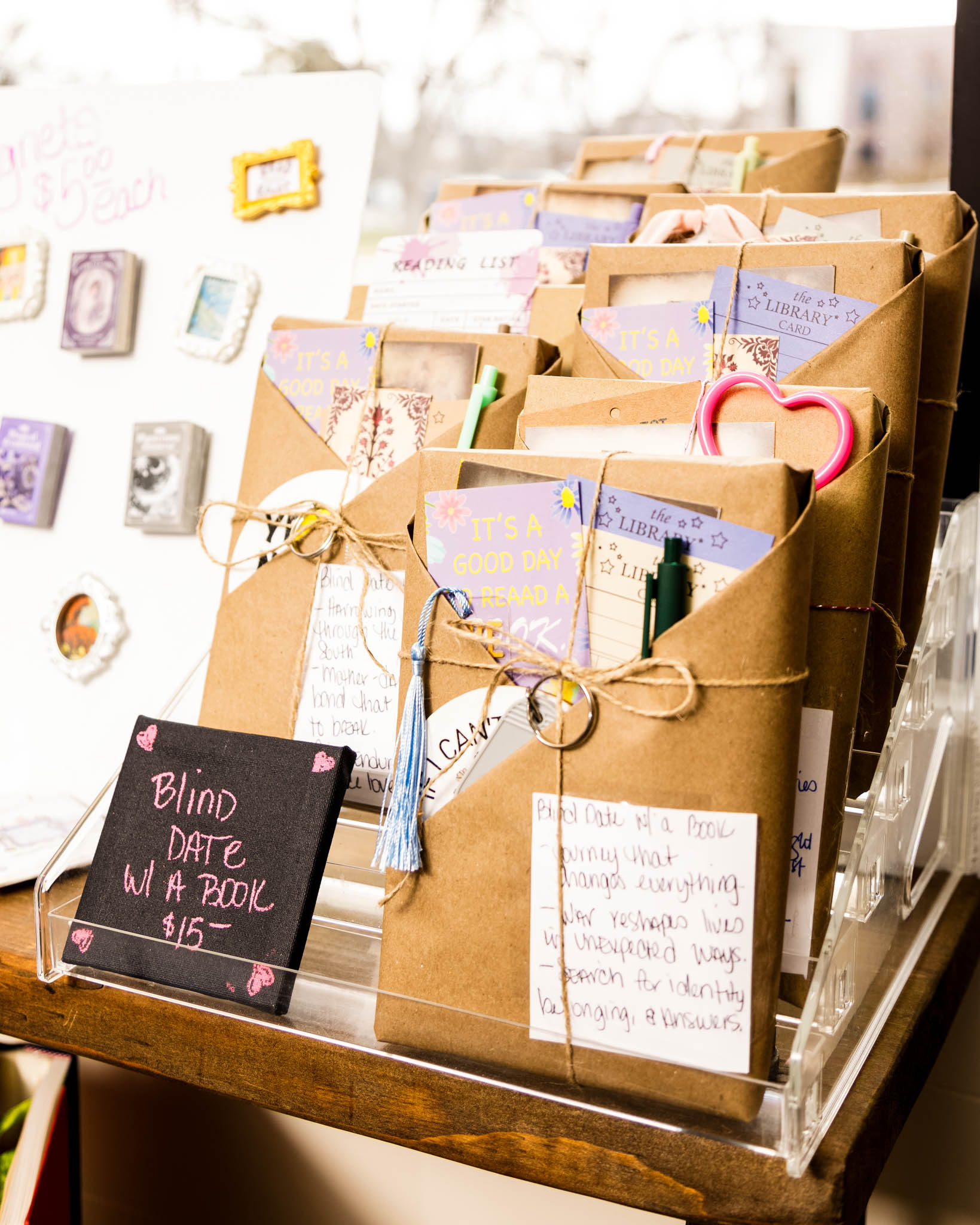Display of brown paper packages with handwritten notes and a small blackboard sign reading 'Blind Date with a Book'.