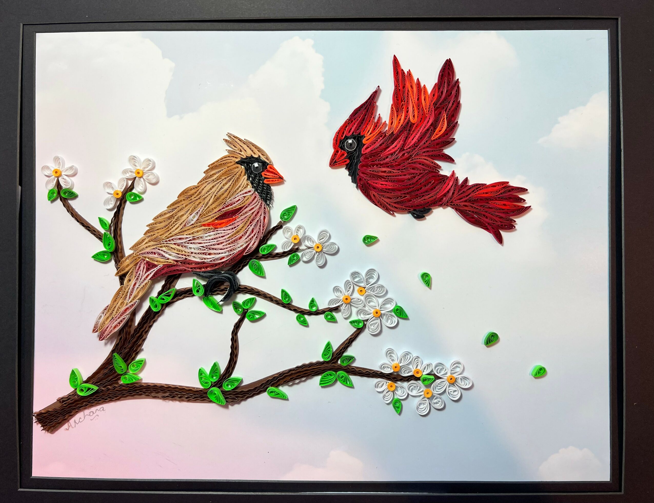 Two colorful birds perched on a flowering branch, one brown and one red, against a light sky background.