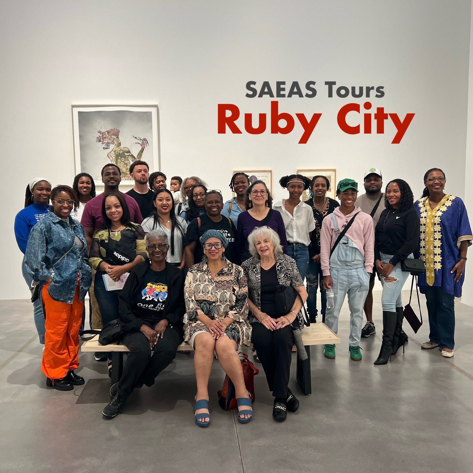 Group of people posing in an art gallery with a sign reading 'SAEAS Tours Ruby City' on the wall behind them.