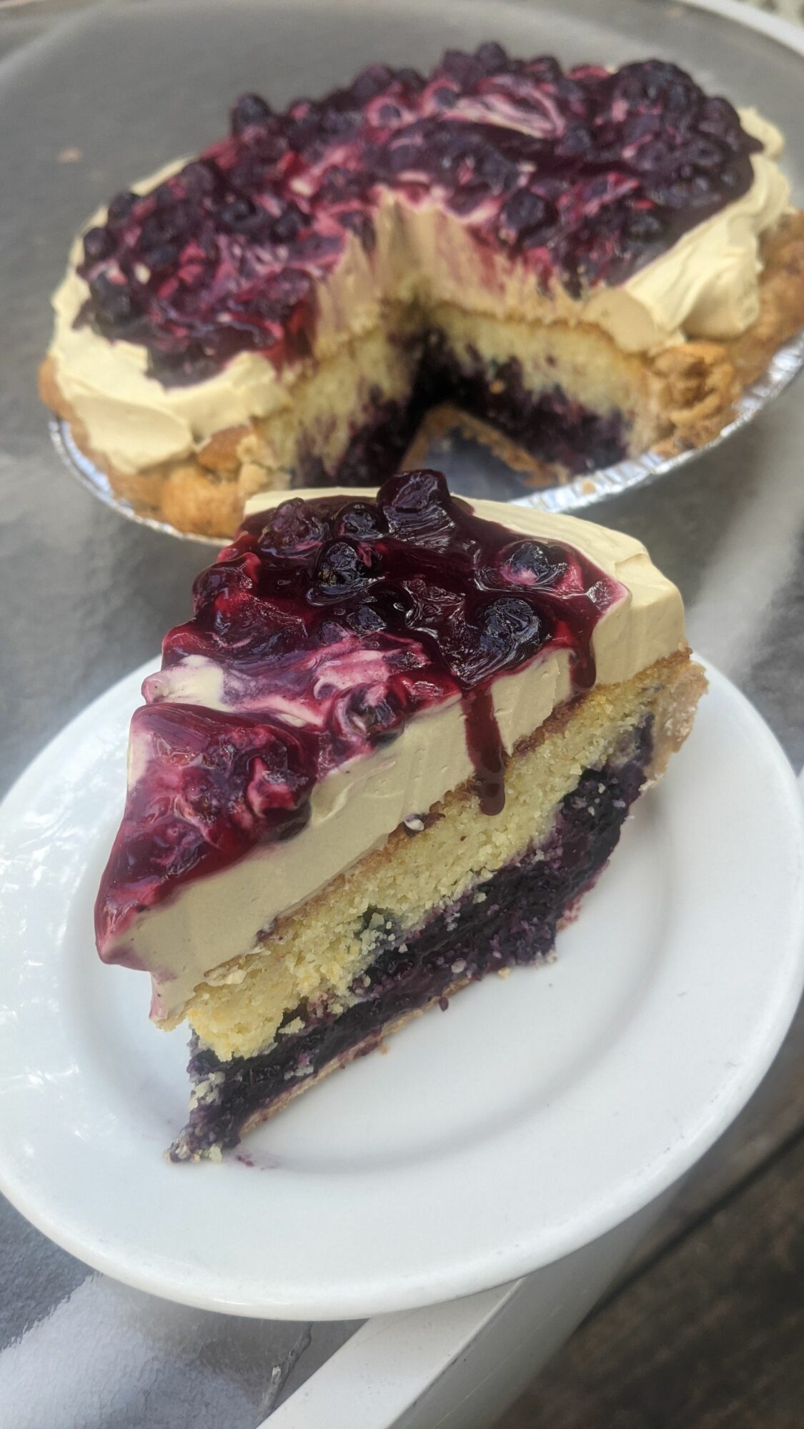 Slice of layered berry dessert with cream and fruit topping on a white plate