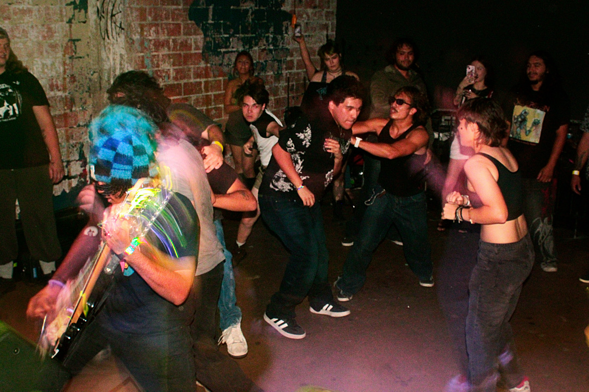 Group of people dancing and socializing in a dimly lit indoor space with brick walls.