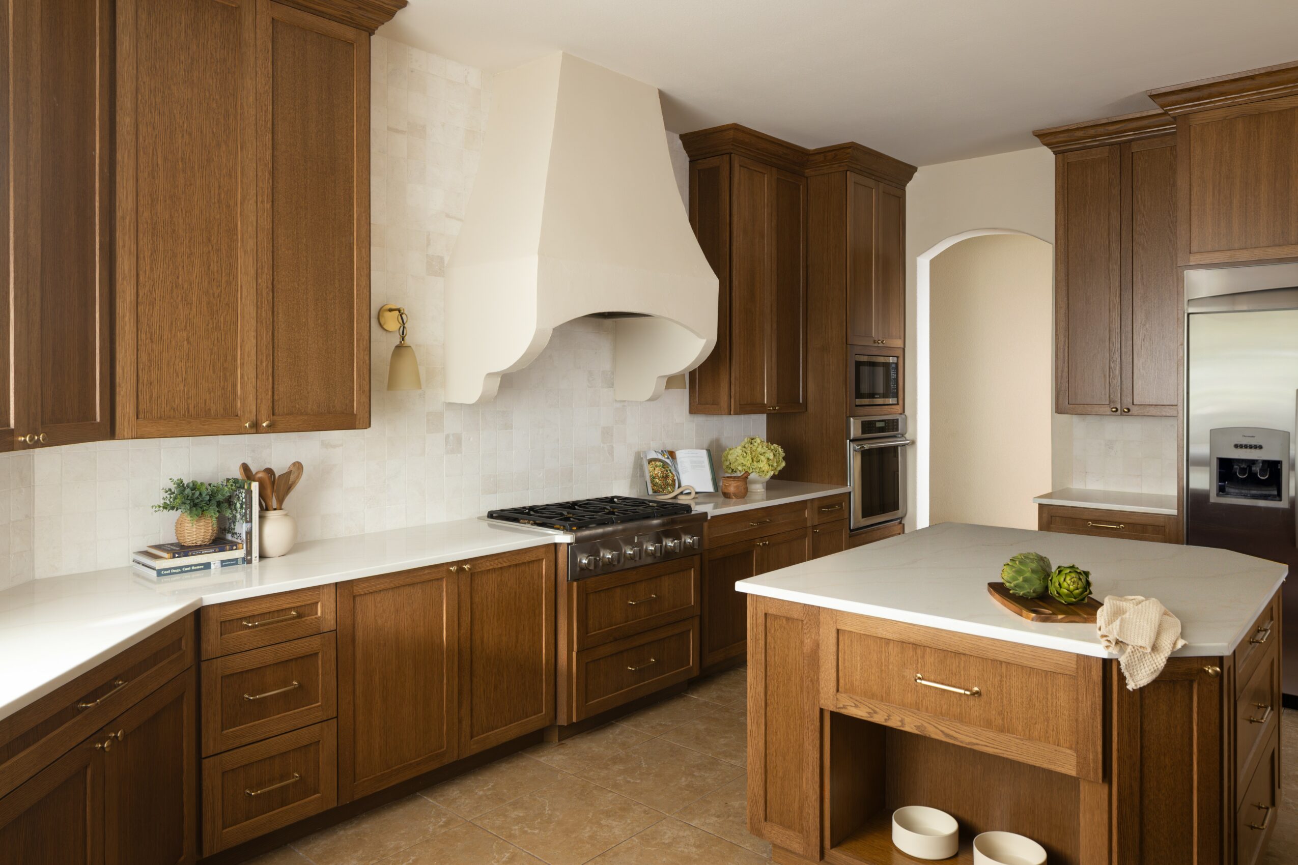 Kitchen with wooden cabinets, white countertops, a stove, and an island with a towel and decorative items.
