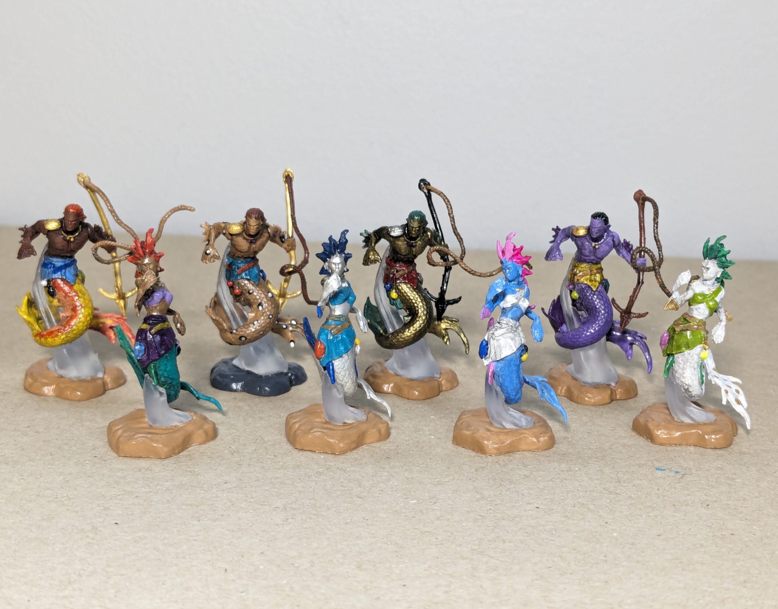 Eight colorful mermaid figurines with different hair and tail colors, standing on small bases, arranged in a row.
