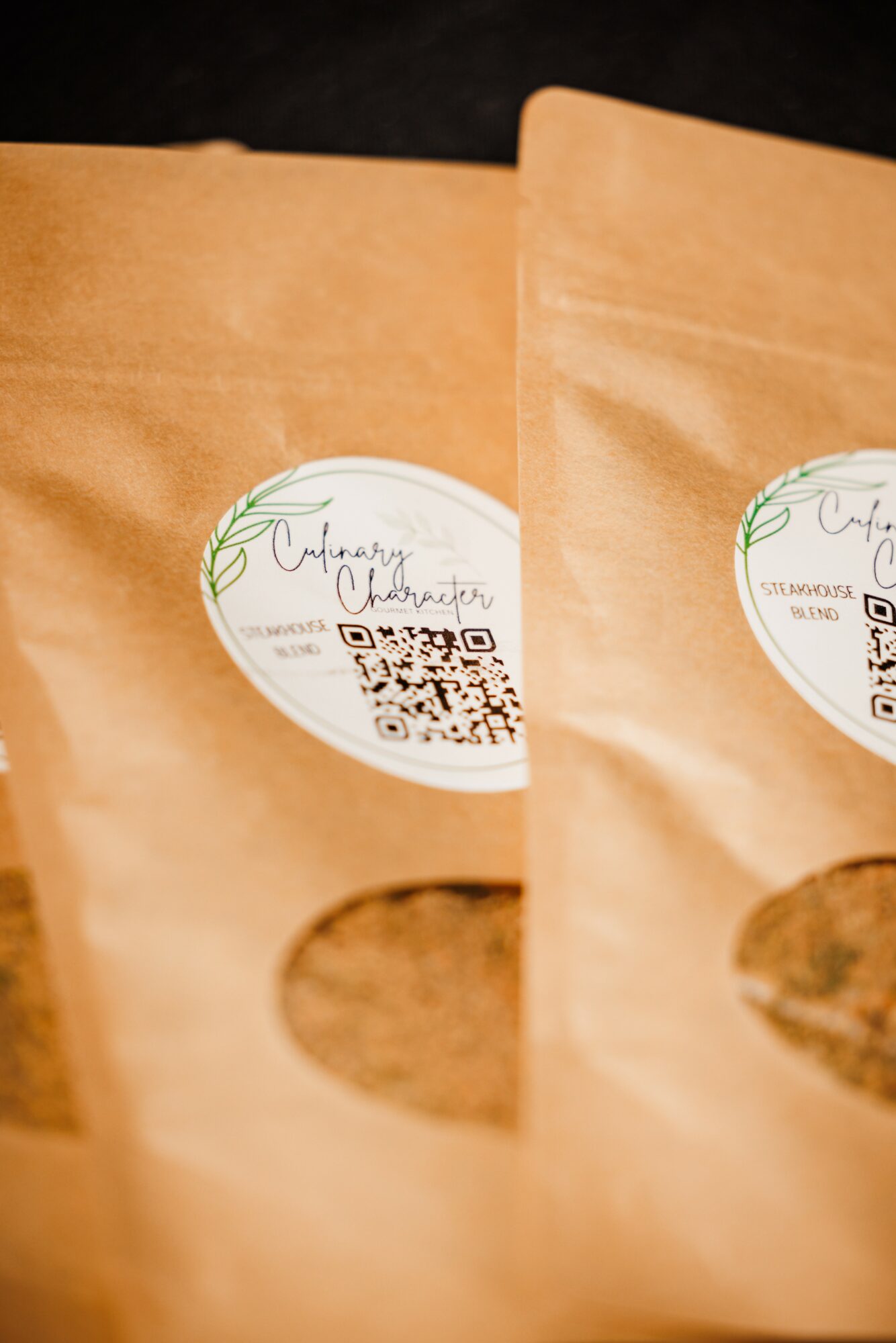 Two brown paper bags with circular labels and transparent windows showing contents, placed on a dark surface.