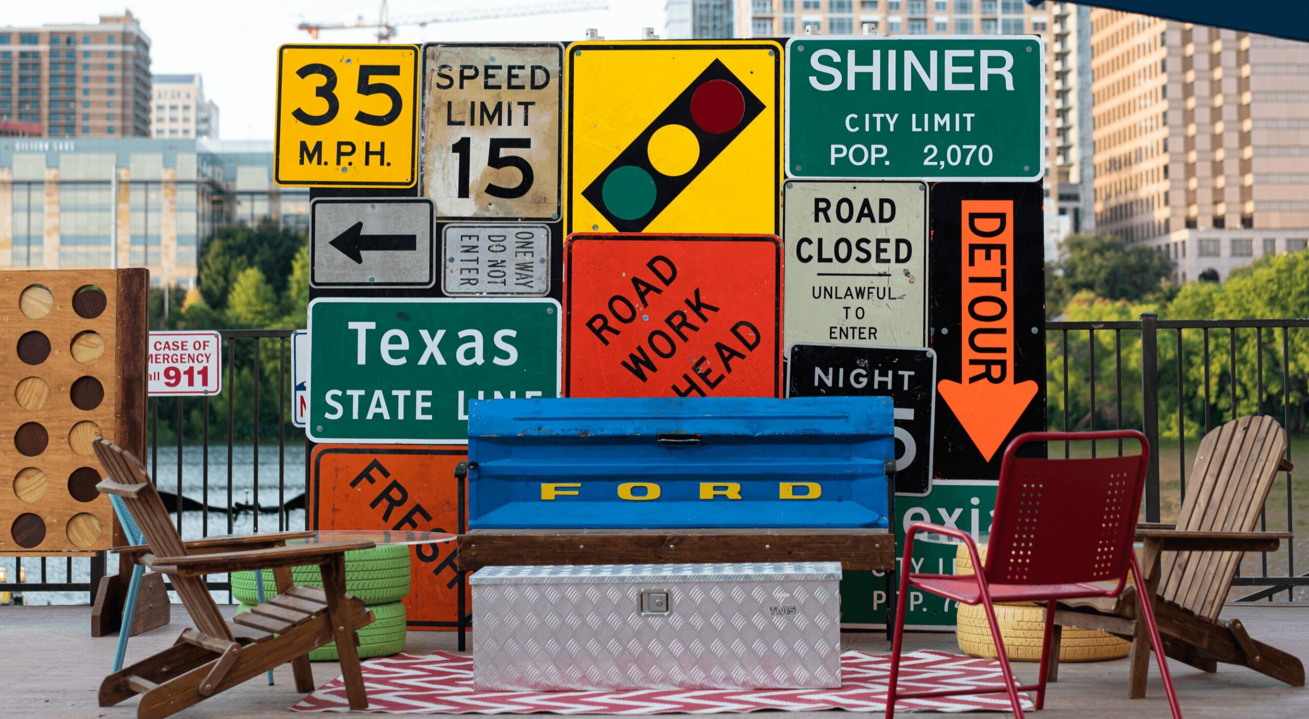 Outdoor scene with traffic signs, benches, and chairs on a city street, with buildings in the background.