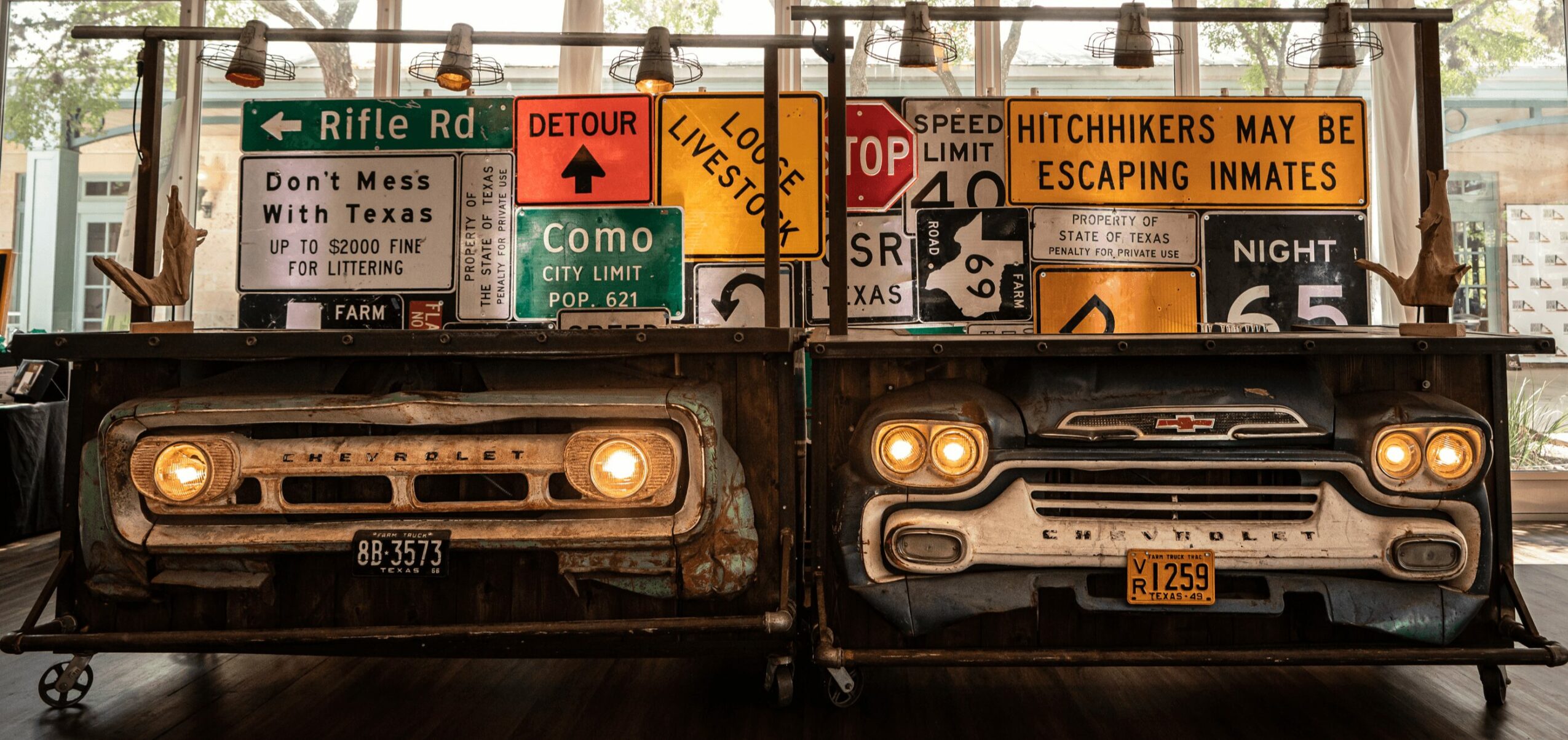 Two cars parked side by side with numerous road signs and billboards behind them, in an indoor setting.