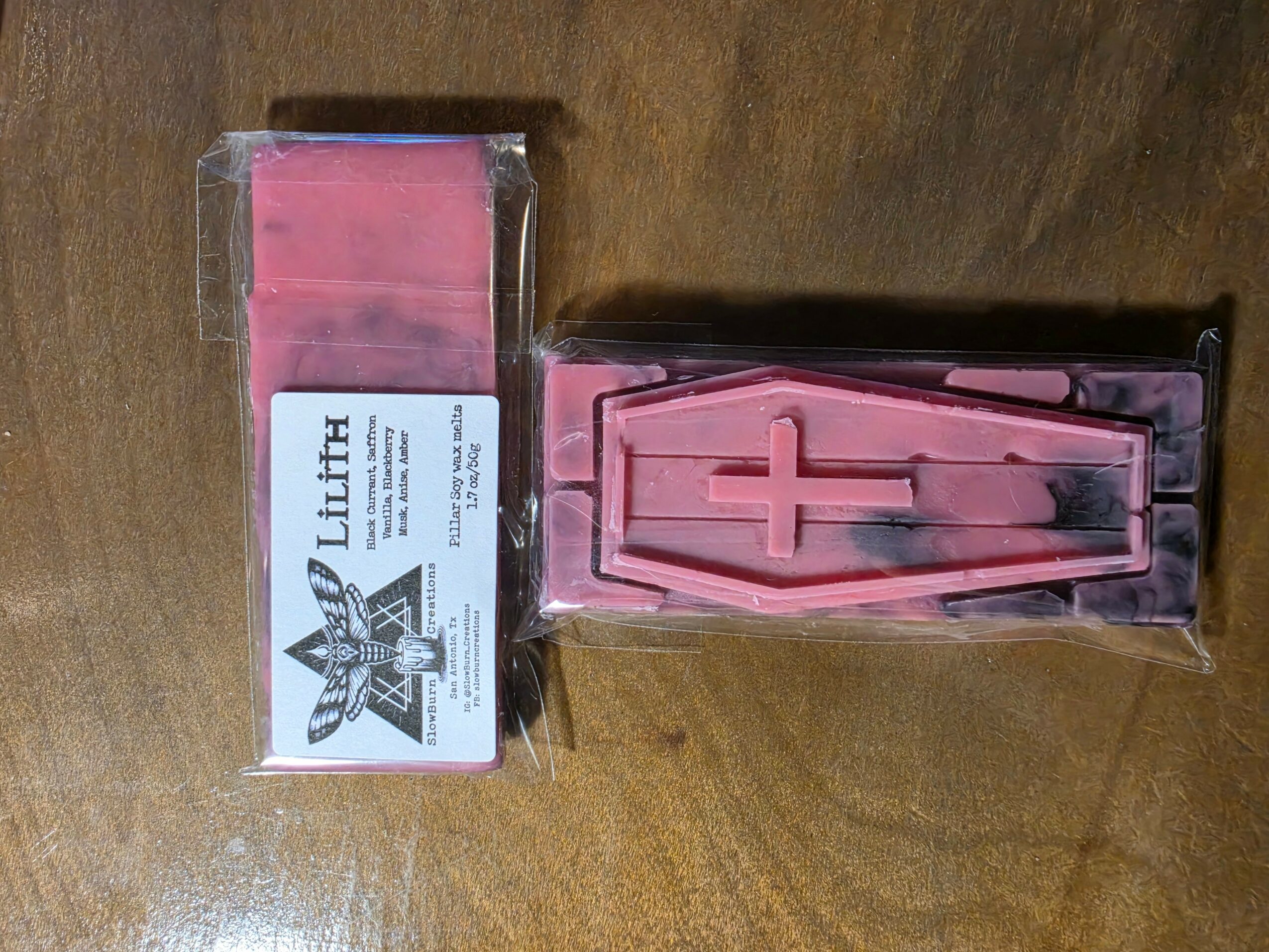 Pink candle in coffin-shaped mold inside plastic packaging, with a box labeled 'Luth' beside it.
