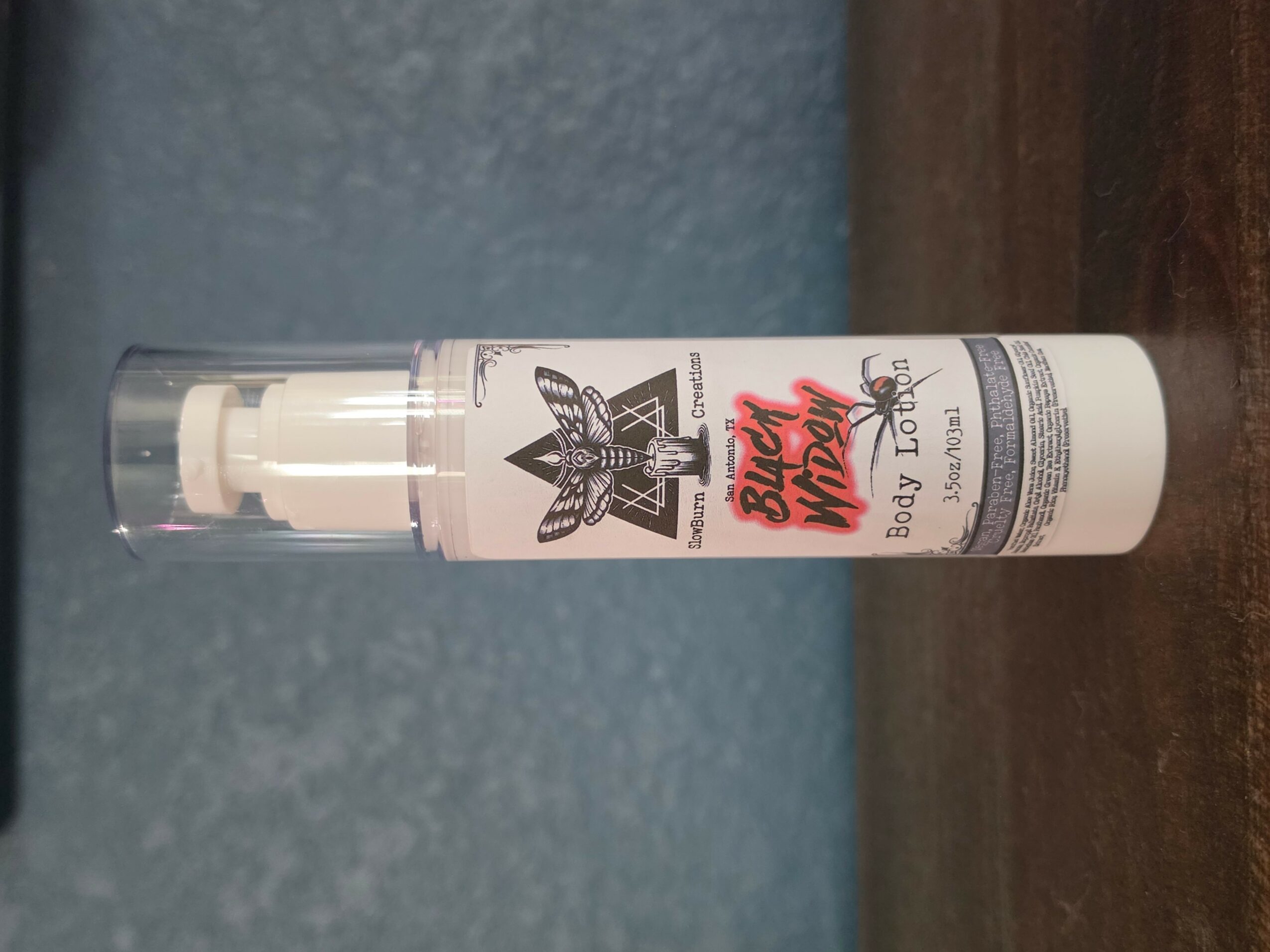 A white spray bottle with a clear cap and label, placed horizontally on a wooden surface.