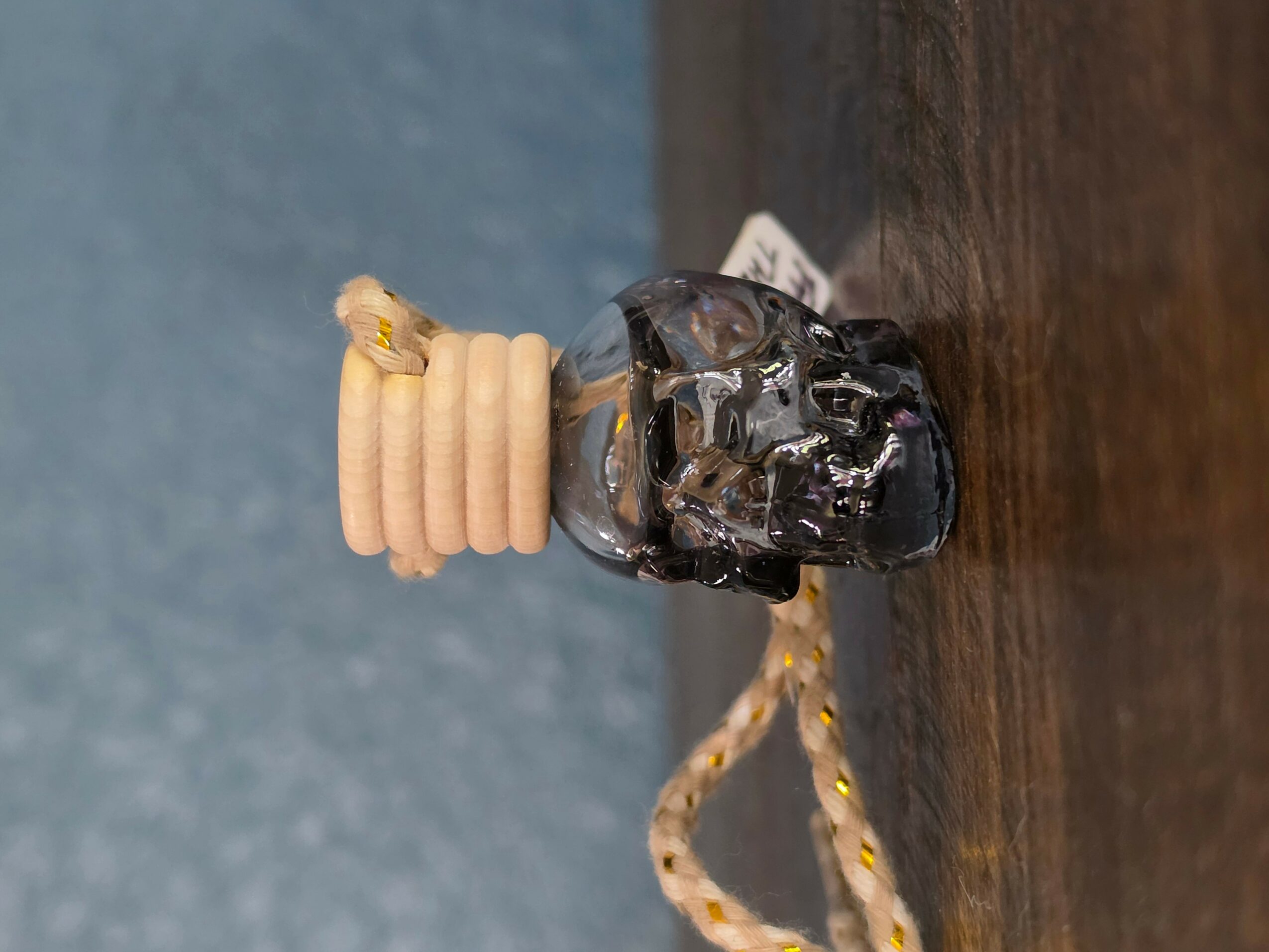 A small sculpture with a black rock, beige coiled object, and a string loop on a wooden surface.