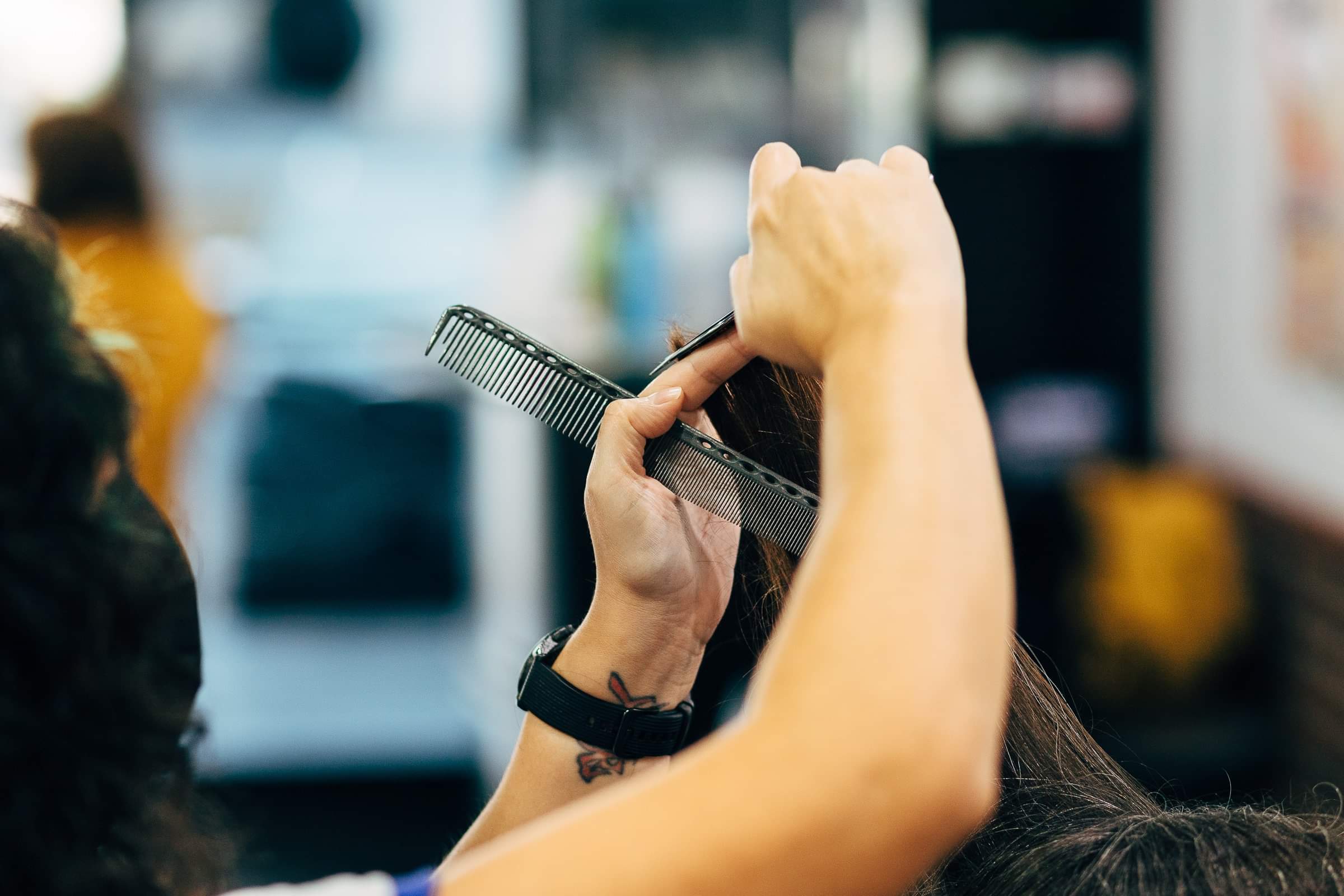 Person holding a comb and a section of long hair in a salon setting.