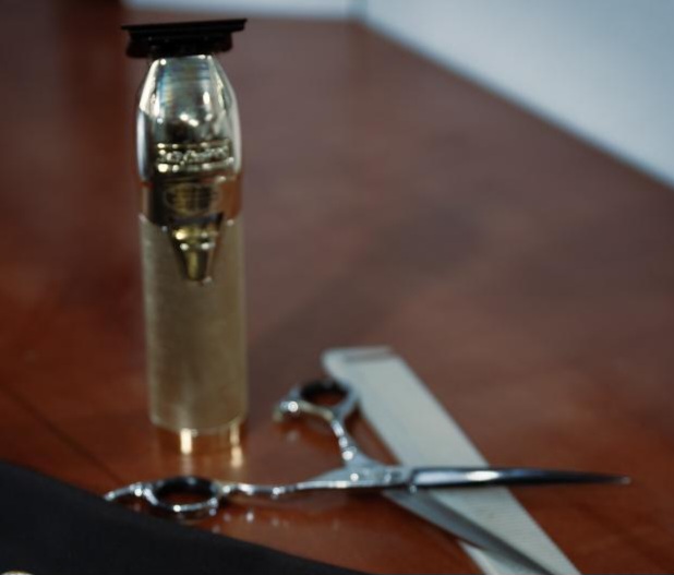 A glass bottle, scissors, and a white object on a wooden surface, with a blurred background.
