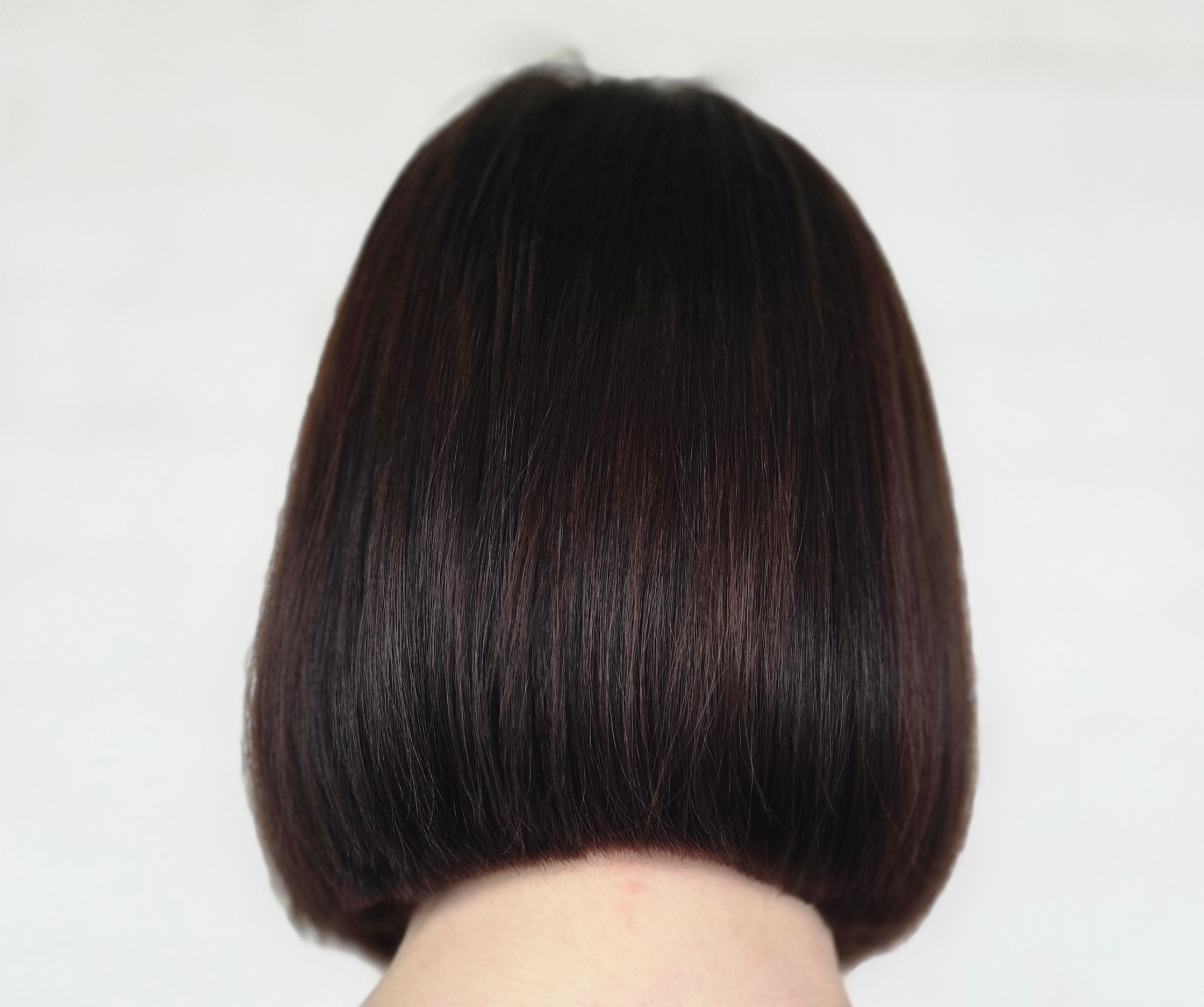 Back of a person's head with a short, straight, dark brown bob haircut.