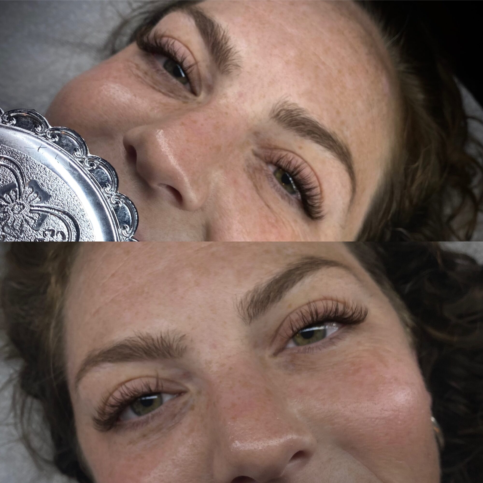 Two women with makeup and freckles lie close together, smiling with eyes partially closed, face-up on a surface.