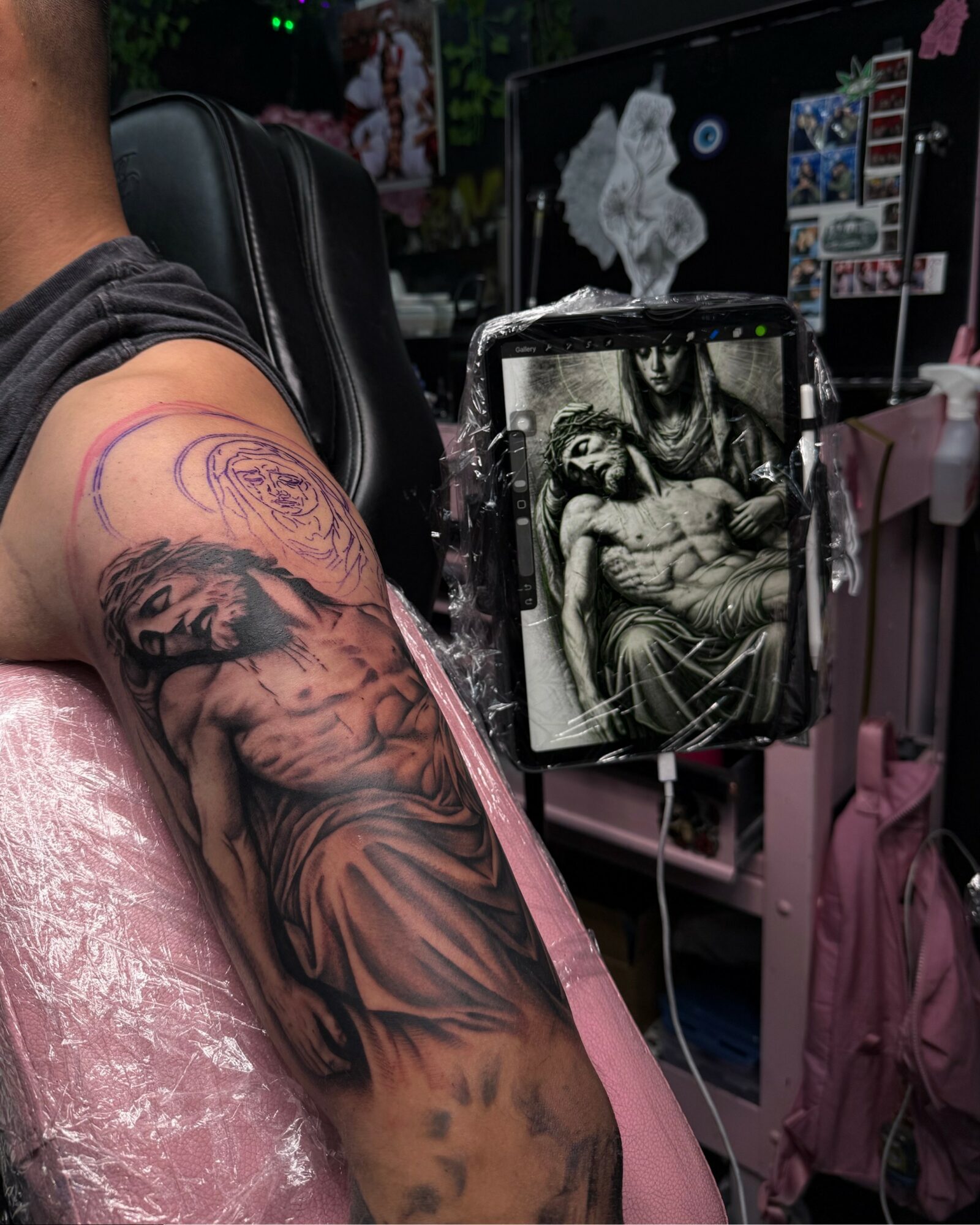 Tattooed arm resting on a pink surface with a detailed black and gray tattoo of a woman and a lion.