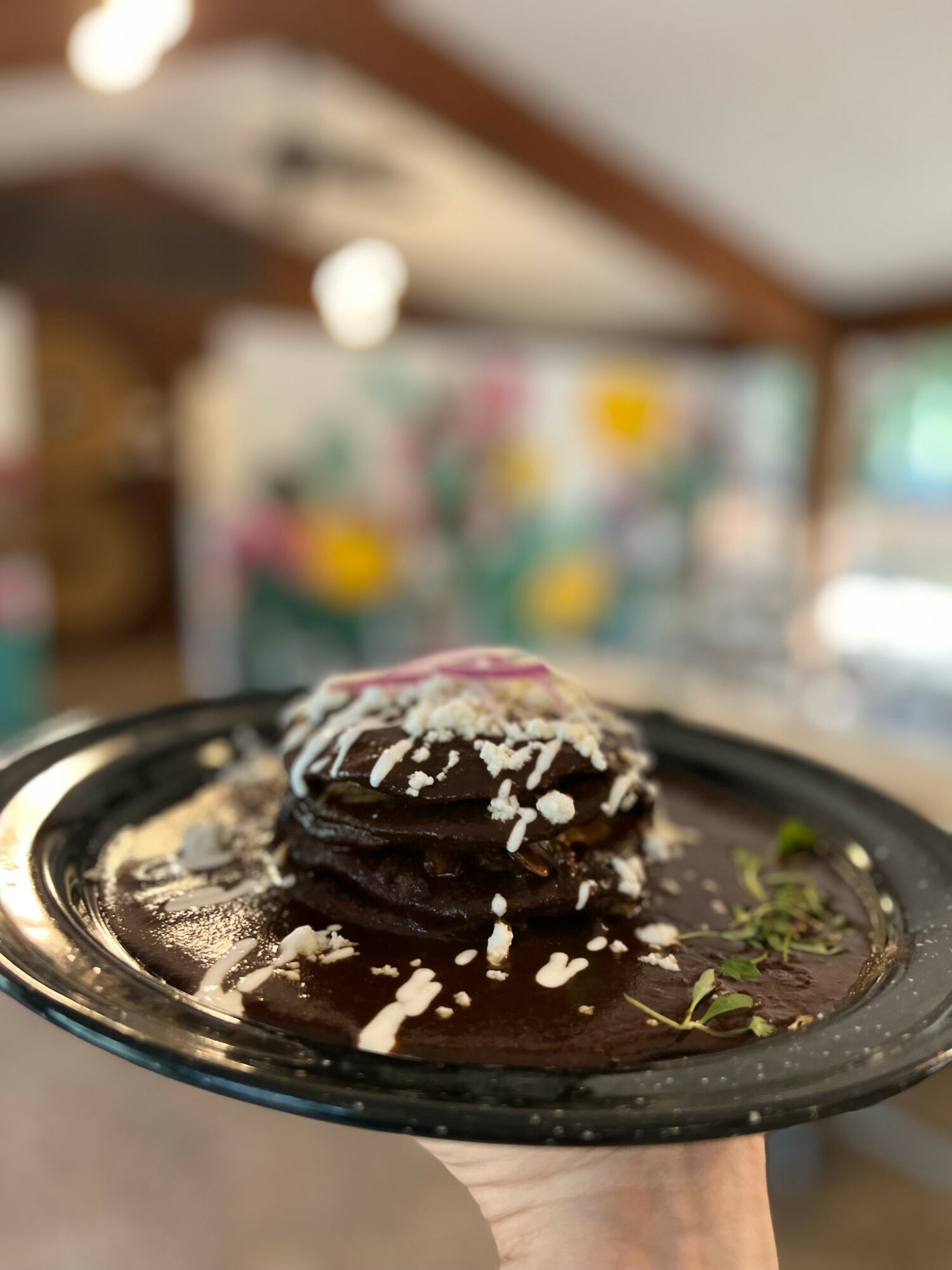 Chocolate cookies with white icing and shredded coconut on a black plate, indoors with blurred background.