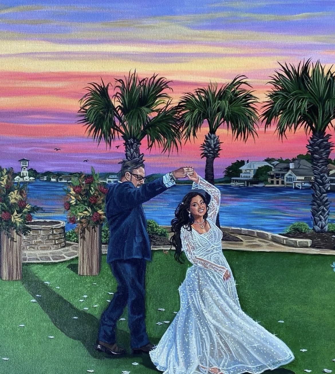 A couple dancing outdoors at sunset with palm trees and water in the background, woman in a white dress, man in a suit.
