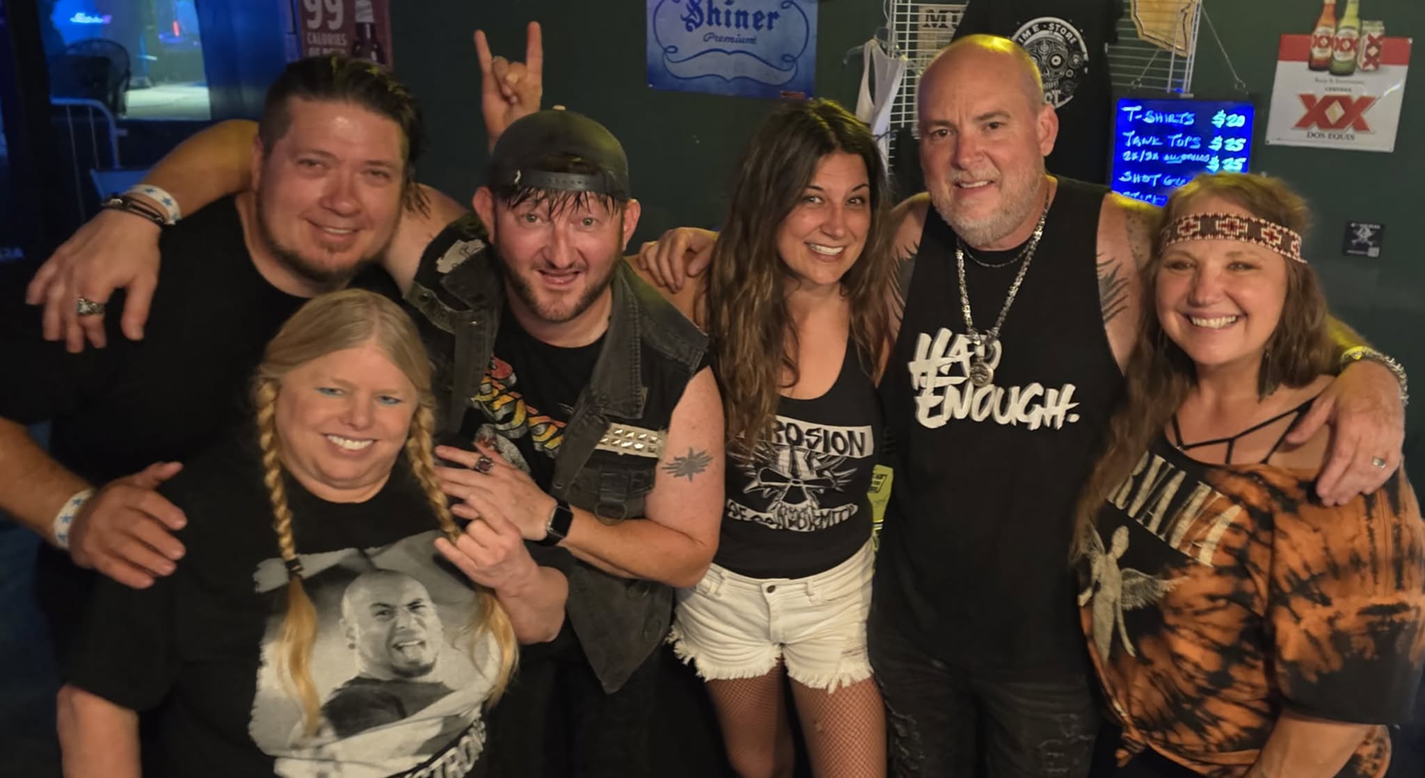 Group of seven people smiling and posing together in a bar or club setting.