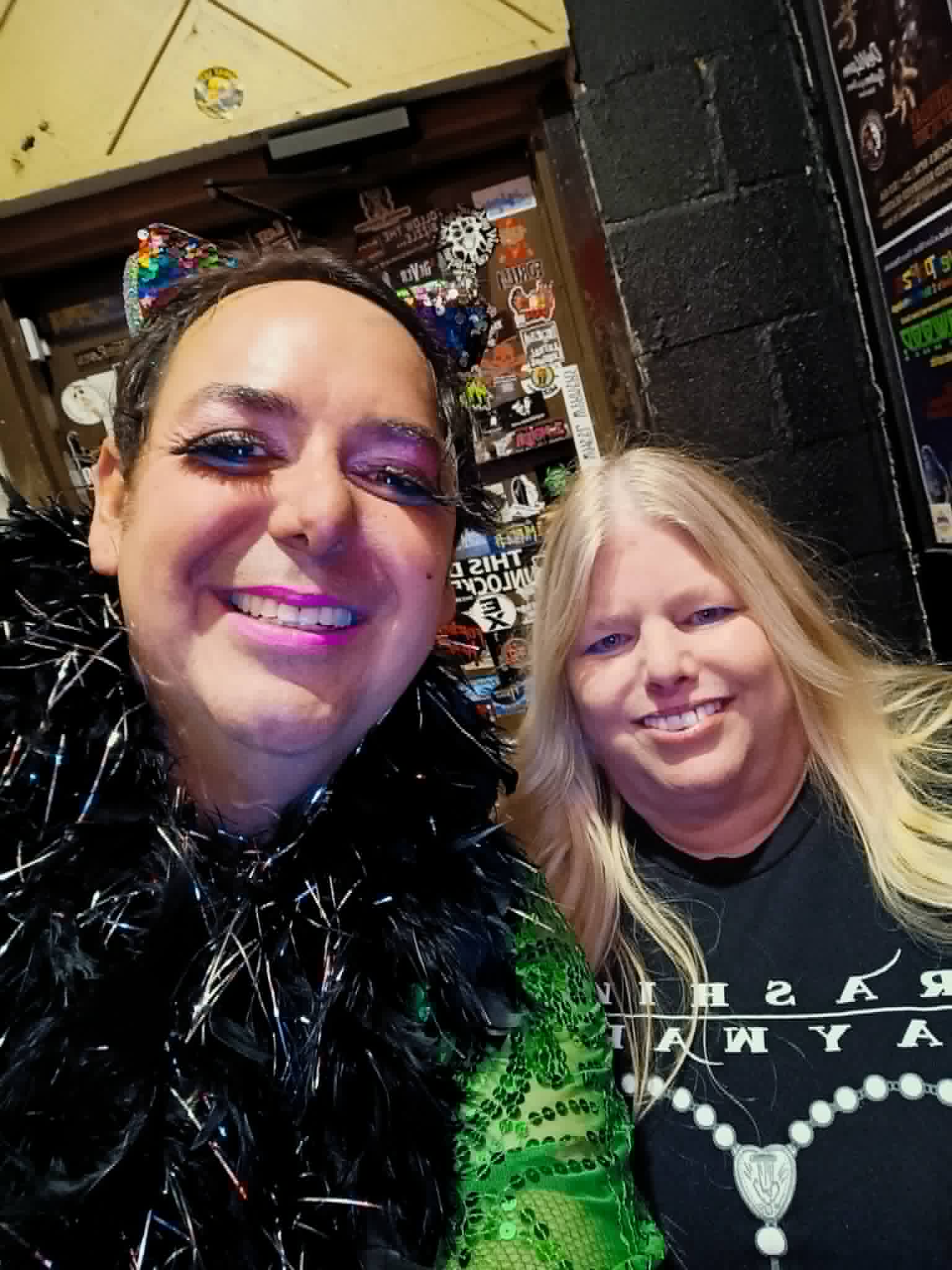 Two smiling women taking a selfie indoors, with shelves and items in the background.