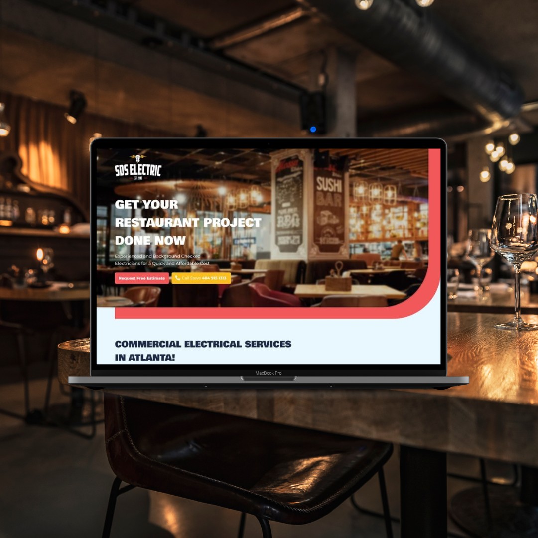 Laptop displaying electrical services website in a dimly lit restaurant or bar setting with tables and glasses.