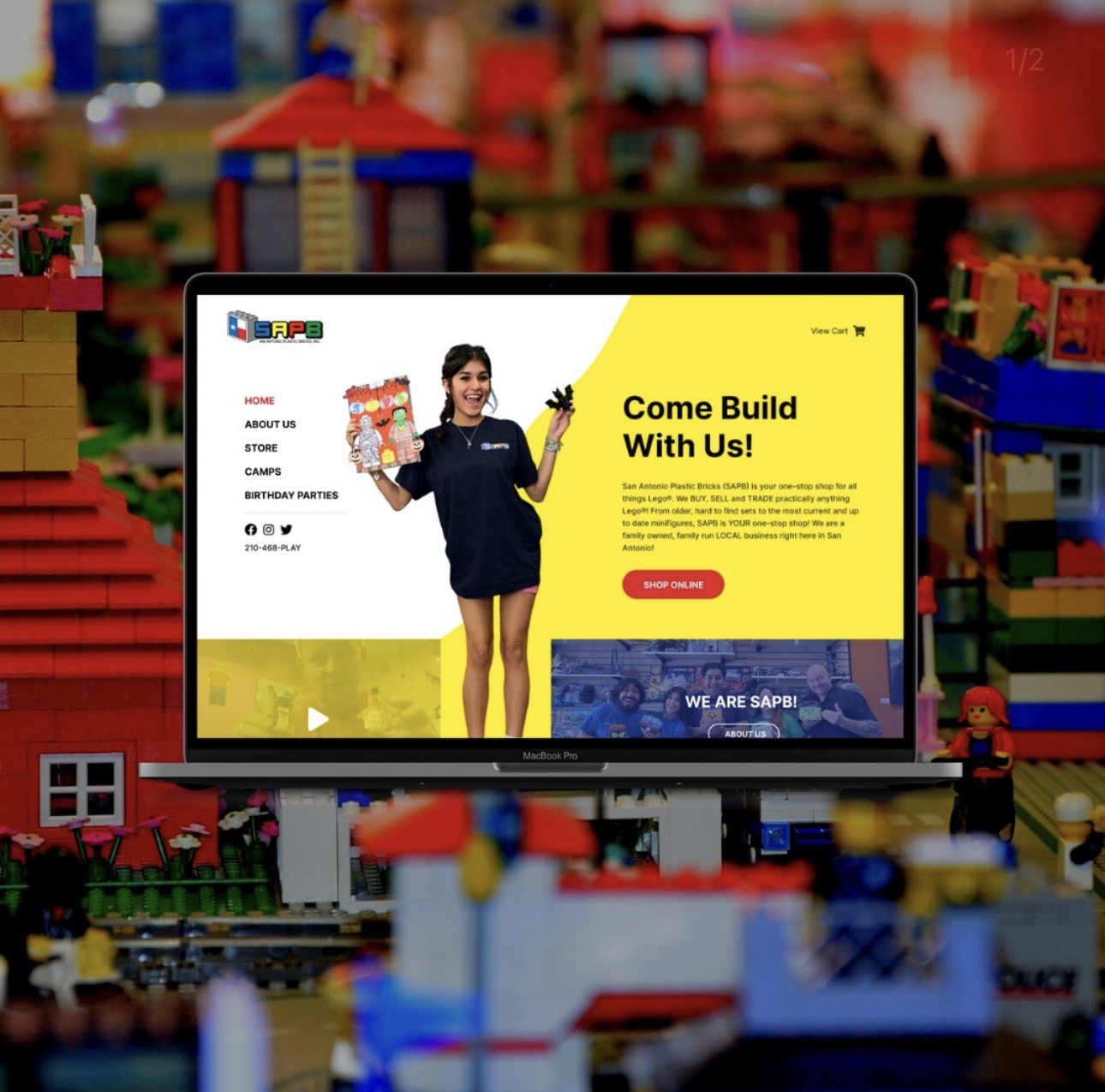 Digital screen displaying a woman in a dark dress holding a LEGO set, with a yellow background and text about building with LEGO.