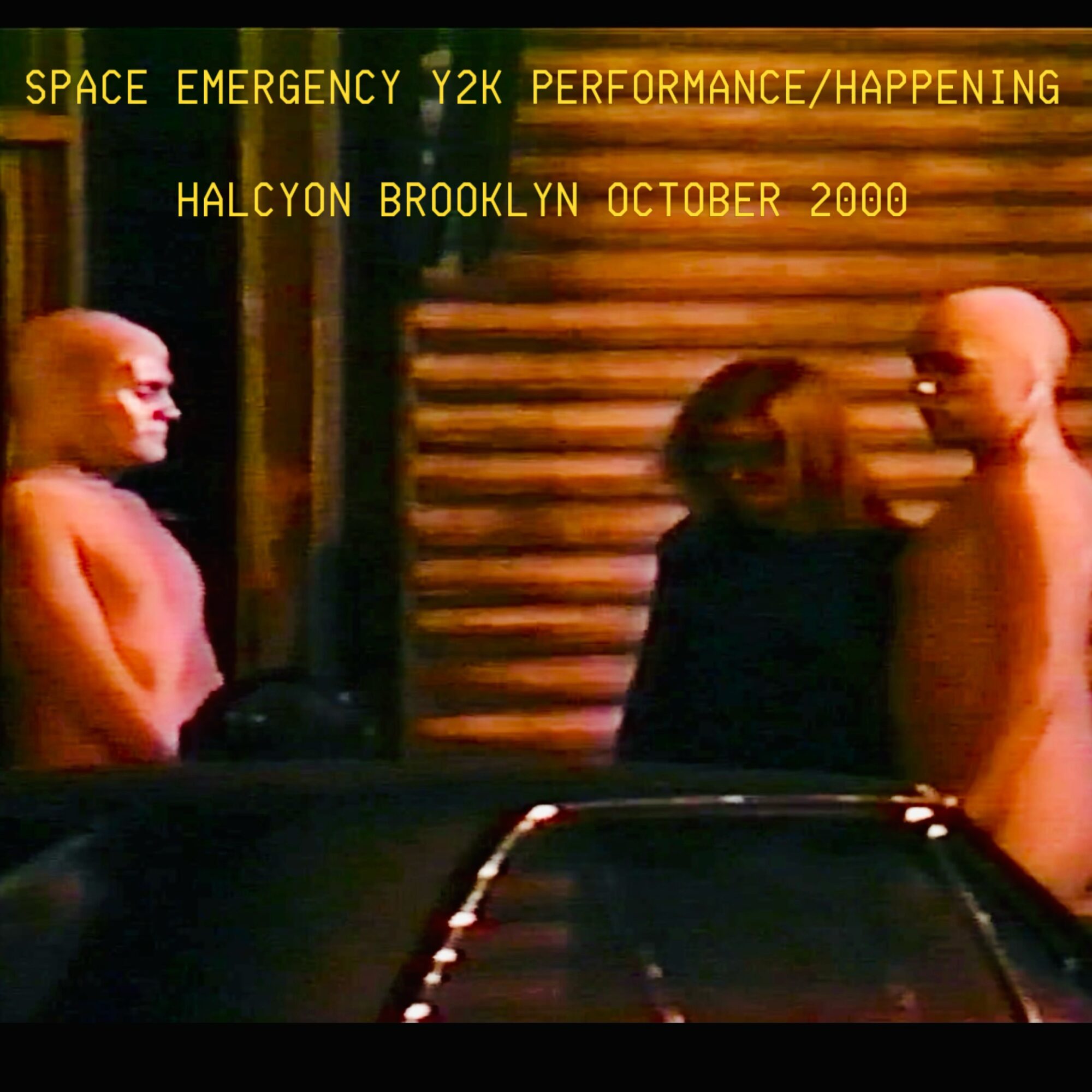 Two shirtless men and a woman standing outside a building with horizontal wooden slats, with text overlay about space emergency event.