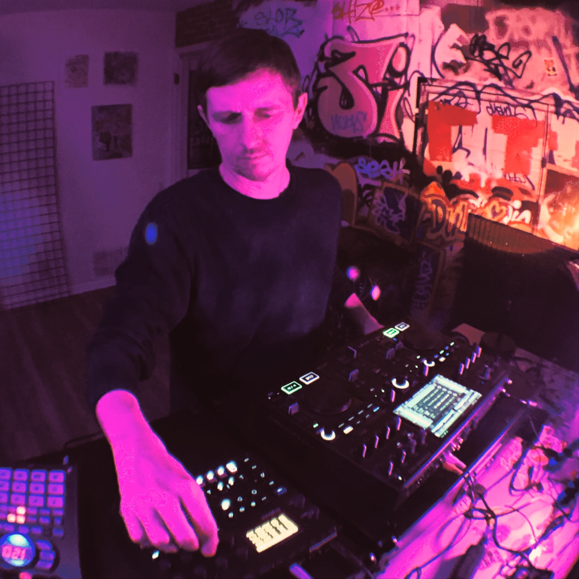 Person DJing with equipment in a room with colorful graffiti art on the wall, purple and pink lighting, and a couch.