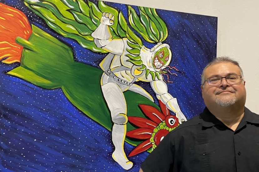 Person with glasses and a black shirt standing next to a colorful, abstract painting of a figure flying through space.