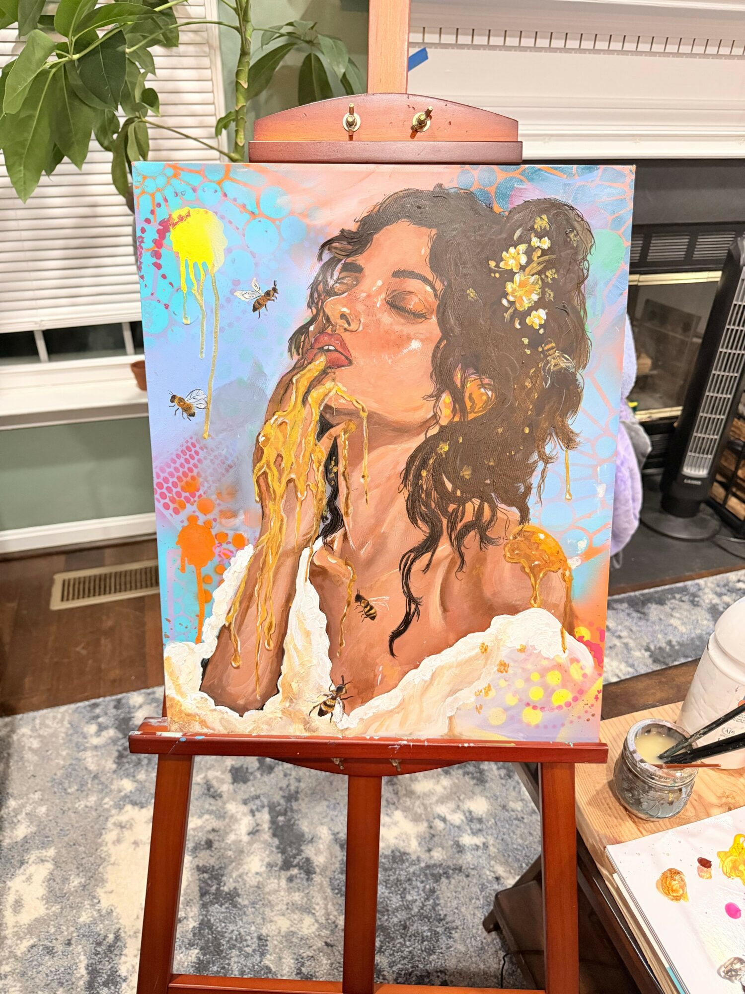 Portrait of a woman with long, curly hair, wearing a floral headband and a white dress, holding a paintbrush.