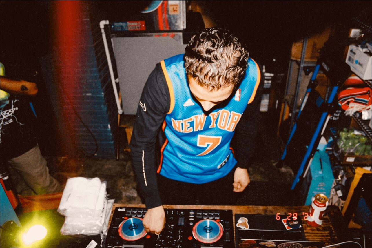 Person wearing a blue New York Knicks basketball jersey with the number 7, playing a game at a gaming console or arcade.