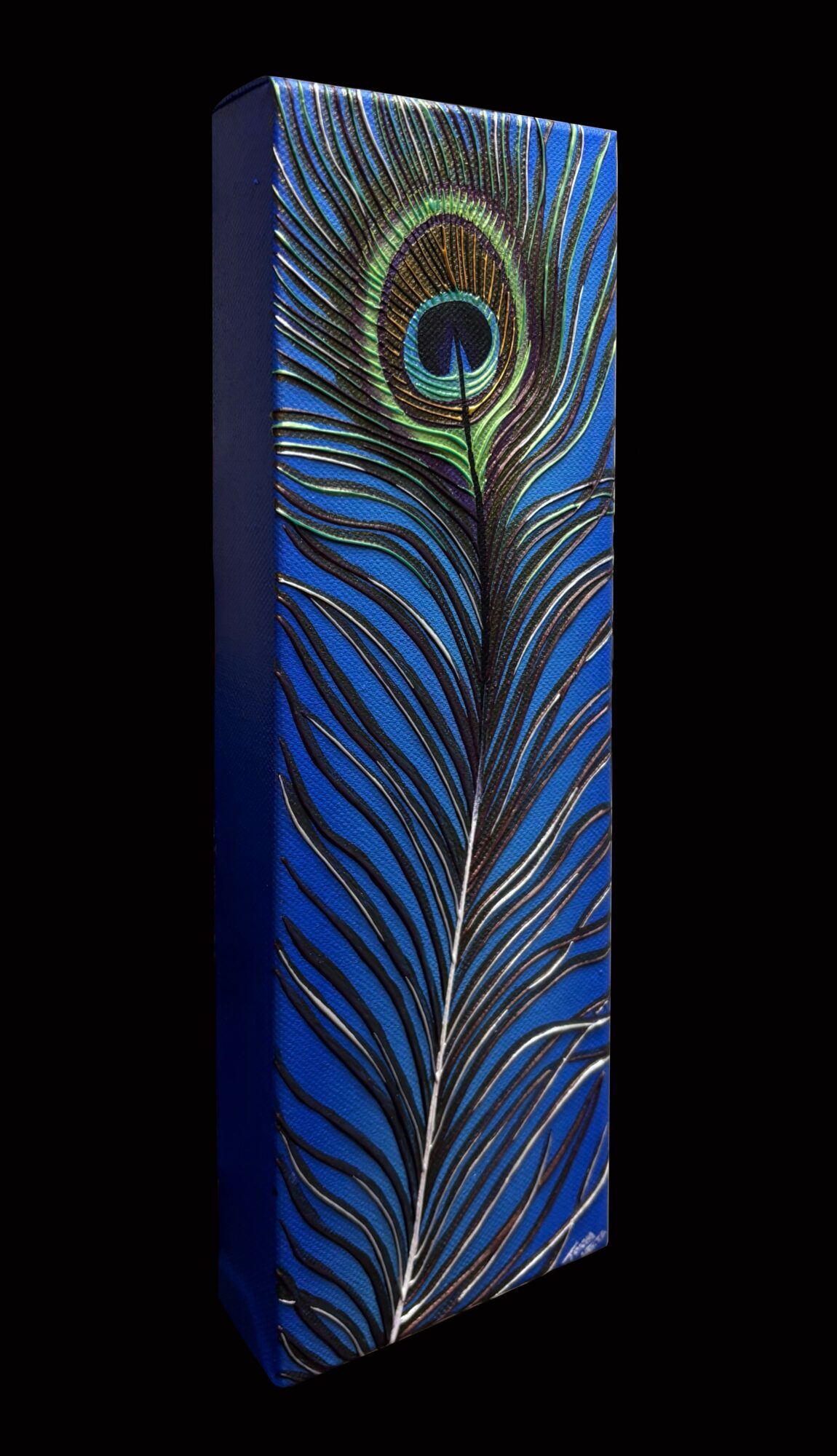 Tall rectangular box with a peacock feather design on a black background, featuring blue, green, and gold colors.