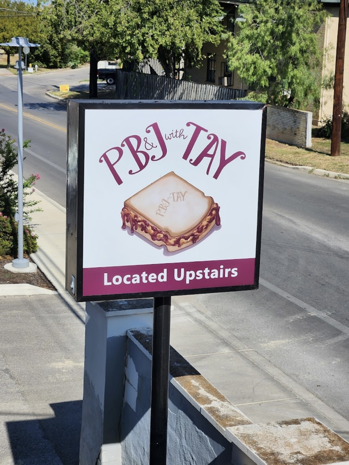 Sign advertising PB&J with TAY, featuring a sandwich image and text indicating upstairs location.