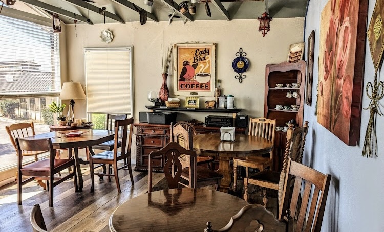 Dining room with wooden tables and chairs, a sideboard, wall art, and a window with blinds.