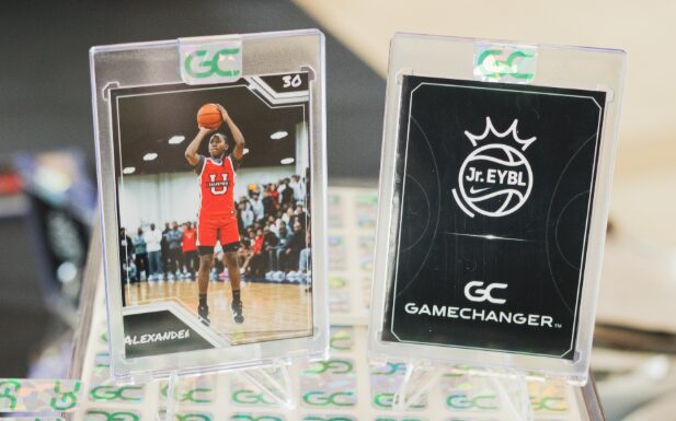 Two basketball trading cards, one showing a player shooting, the other with a logo, on a table with blurred background.