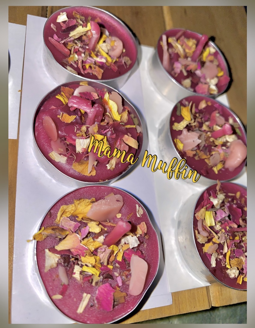 Six pink muffins topped with colorful sprinkles and decorations on white paper, placed on a wooden surface.