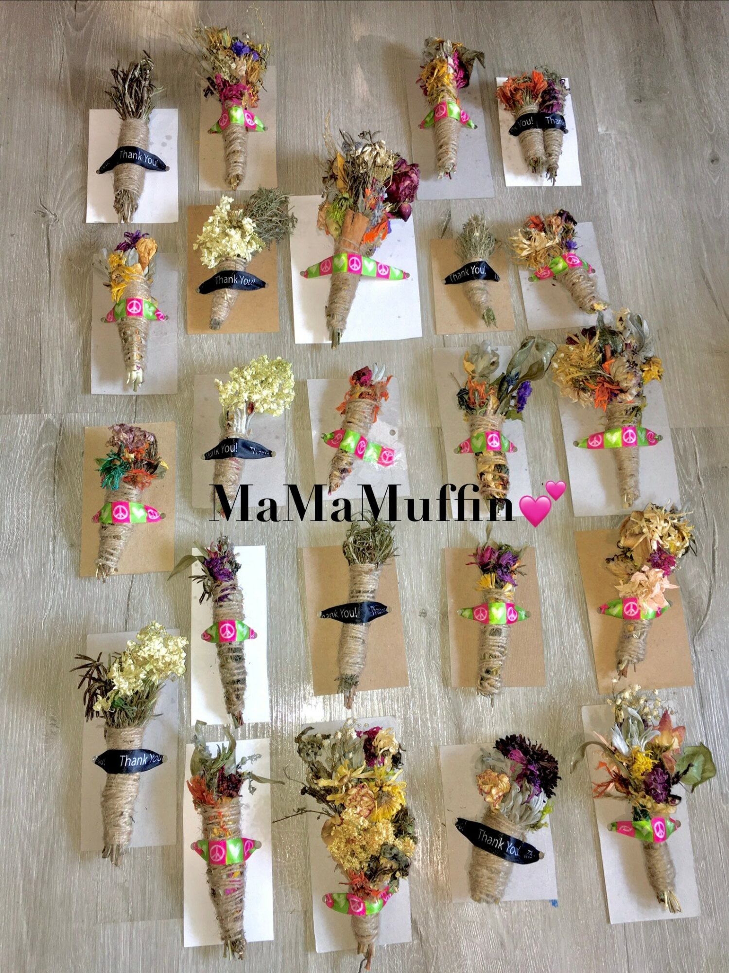 Multiple small bouquets of dried flowers on paper cones, arranged in rows on a wooden surface, with text 'MaMa Muffin' and a pink heart.
