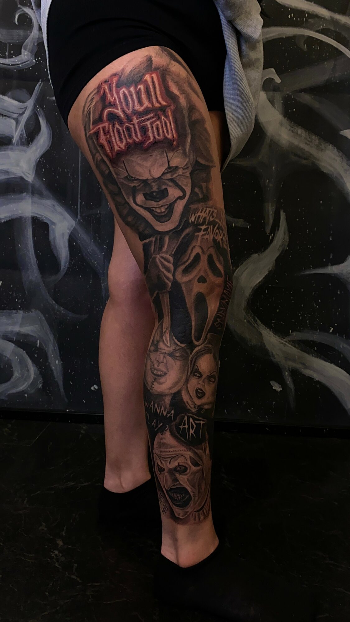 Tattooed arm with a skull, text, and various detailed designs, including a woman's face and abstract elements.