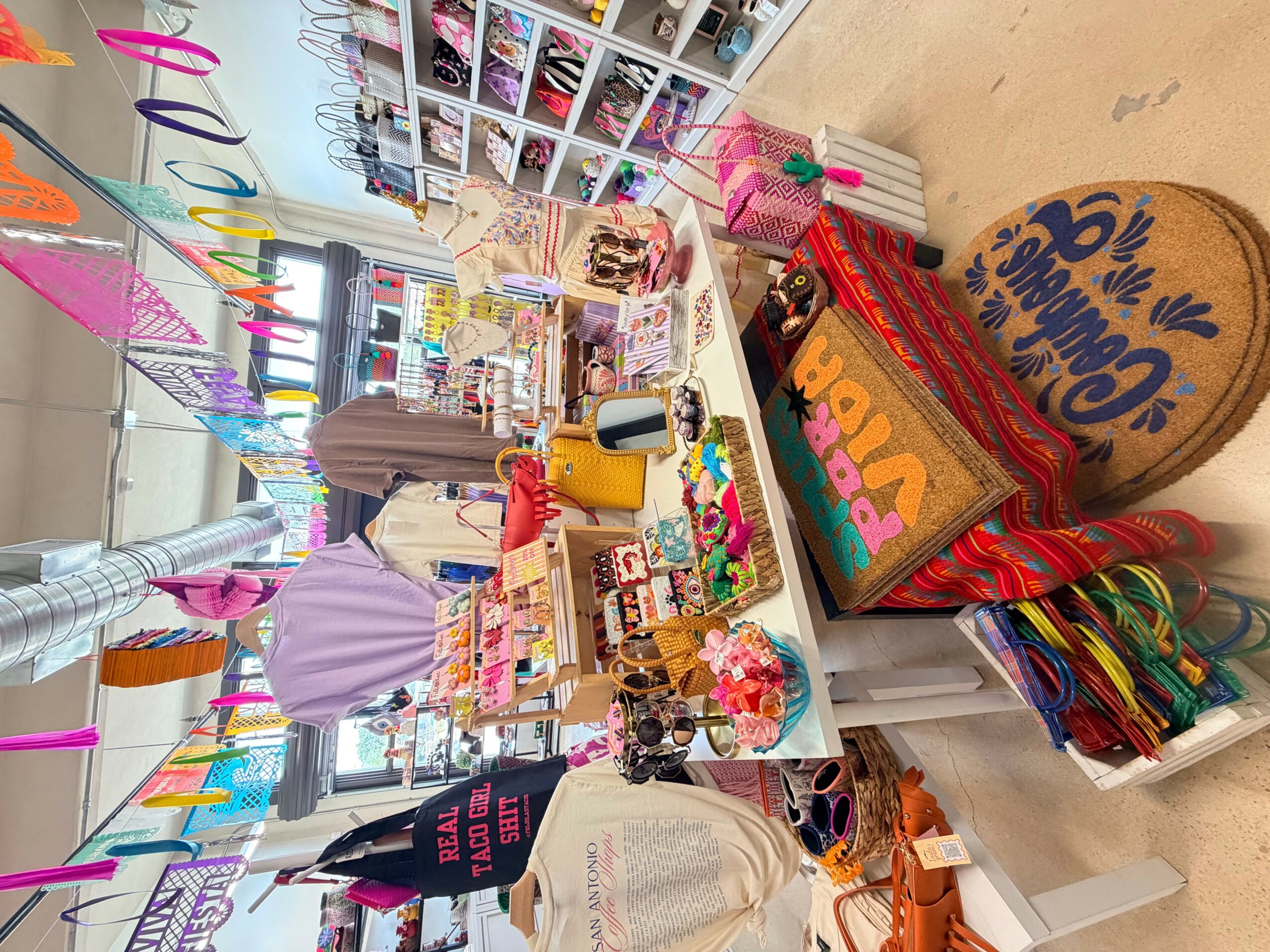Table with colorful decorations, gifts, and party supplies in a decorated room, with a person in a purple shirt and a black hat.